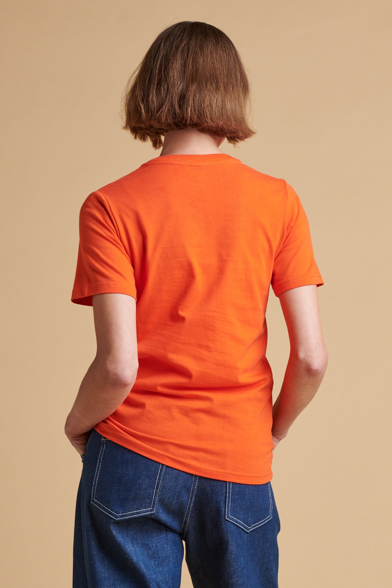 The back of female wearing short sleeve t shirt in flame red.