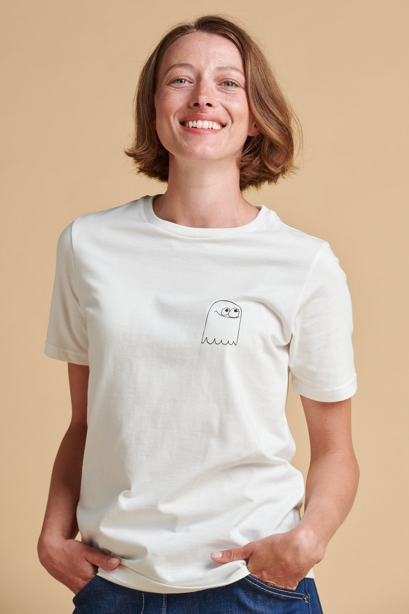 Person wearing a white t-shirt with a small graphic on a beige background