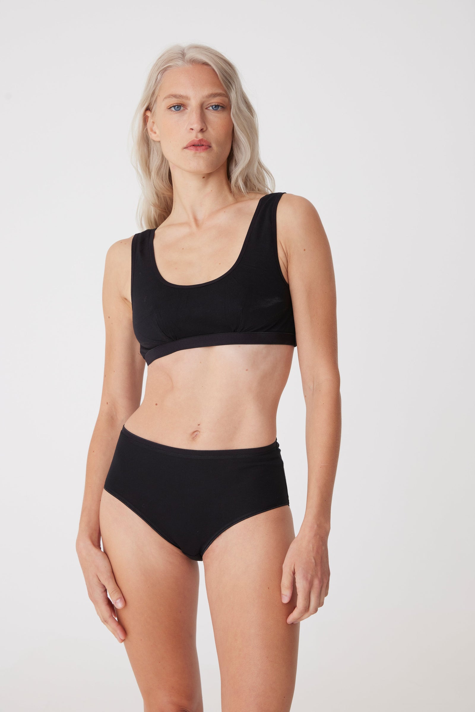 Plus sized white female with cropped blonde hair wearing a black soft jersey bra and black knickers from community clothing