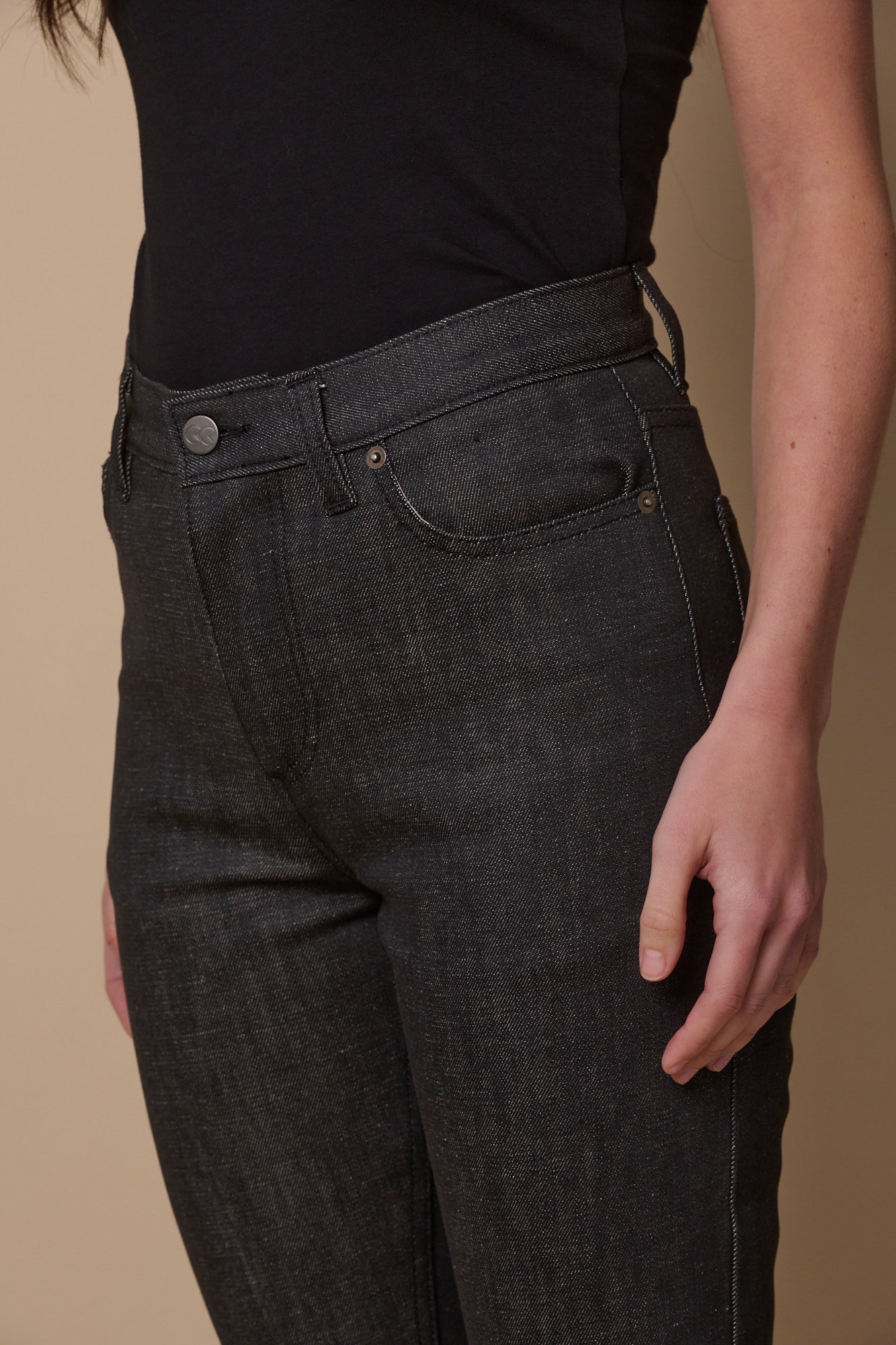 Close up image of female wearing straight leg high rise jeans in black with front  pockets and belt loops
