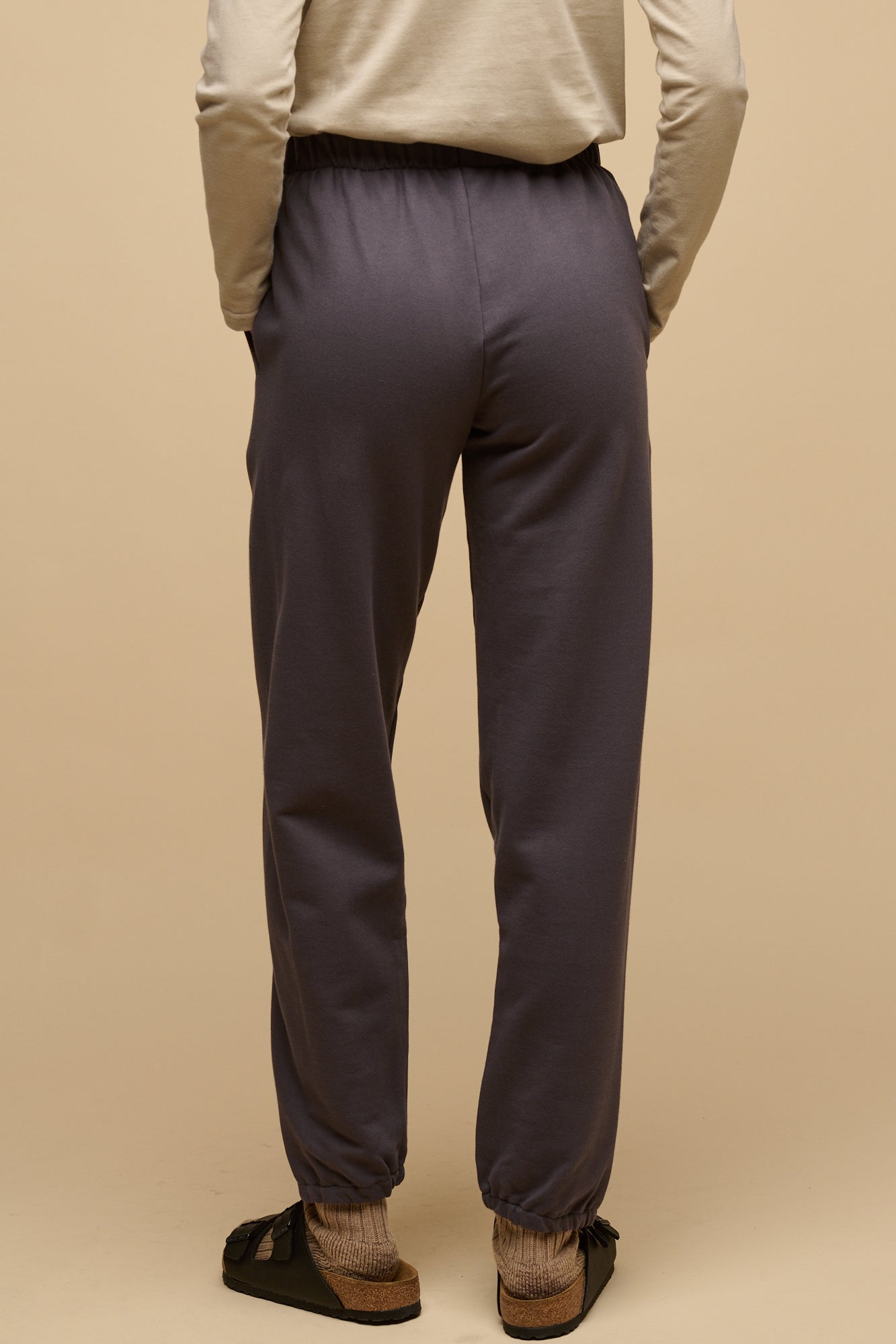 Waist down of the back of female wearing sweatpants in slate grey with hands in front pockets