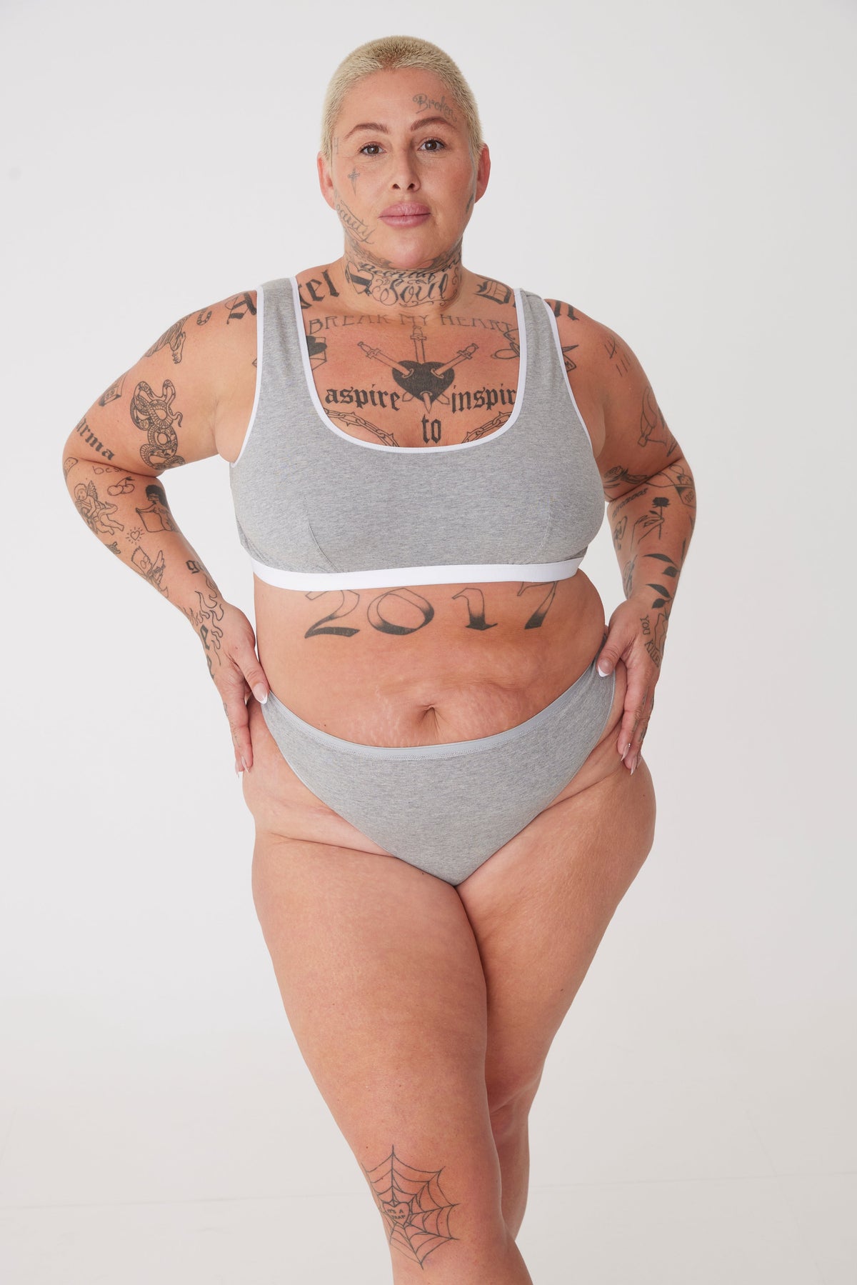 tattooed, white female wearing grey thong paired with grey soft jersey bra