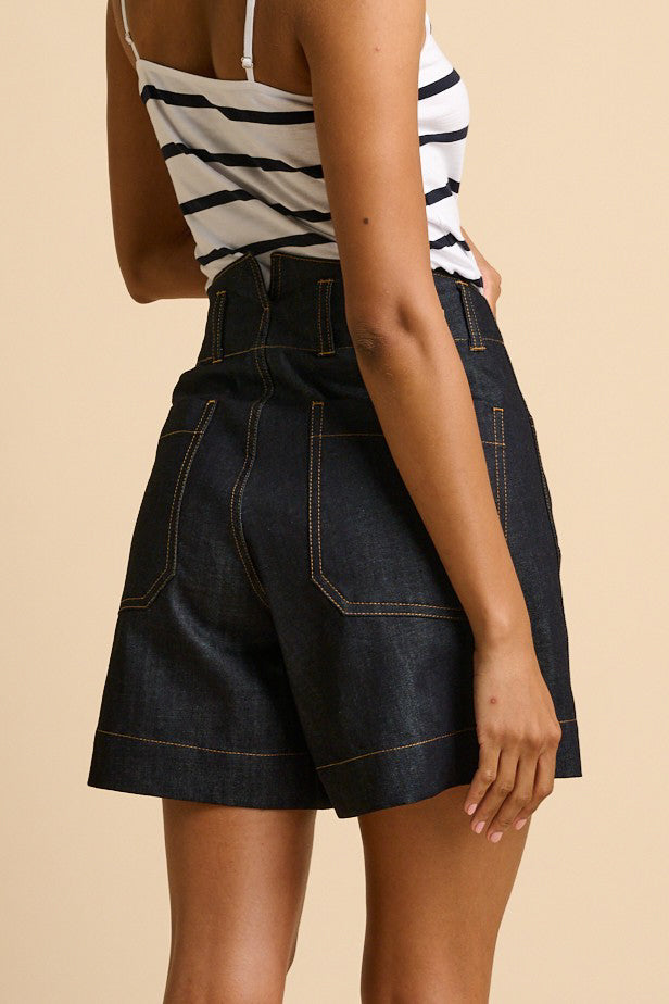 Person wearing a striped top and denim shorts on a beige background