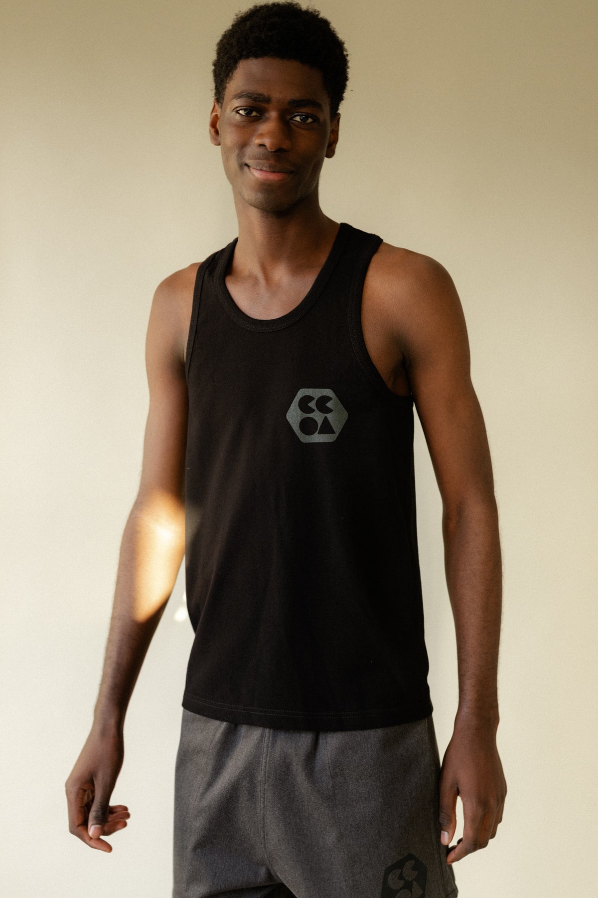 Smiley male wearing breathable racer back vest plastic free in black with CCOA logo