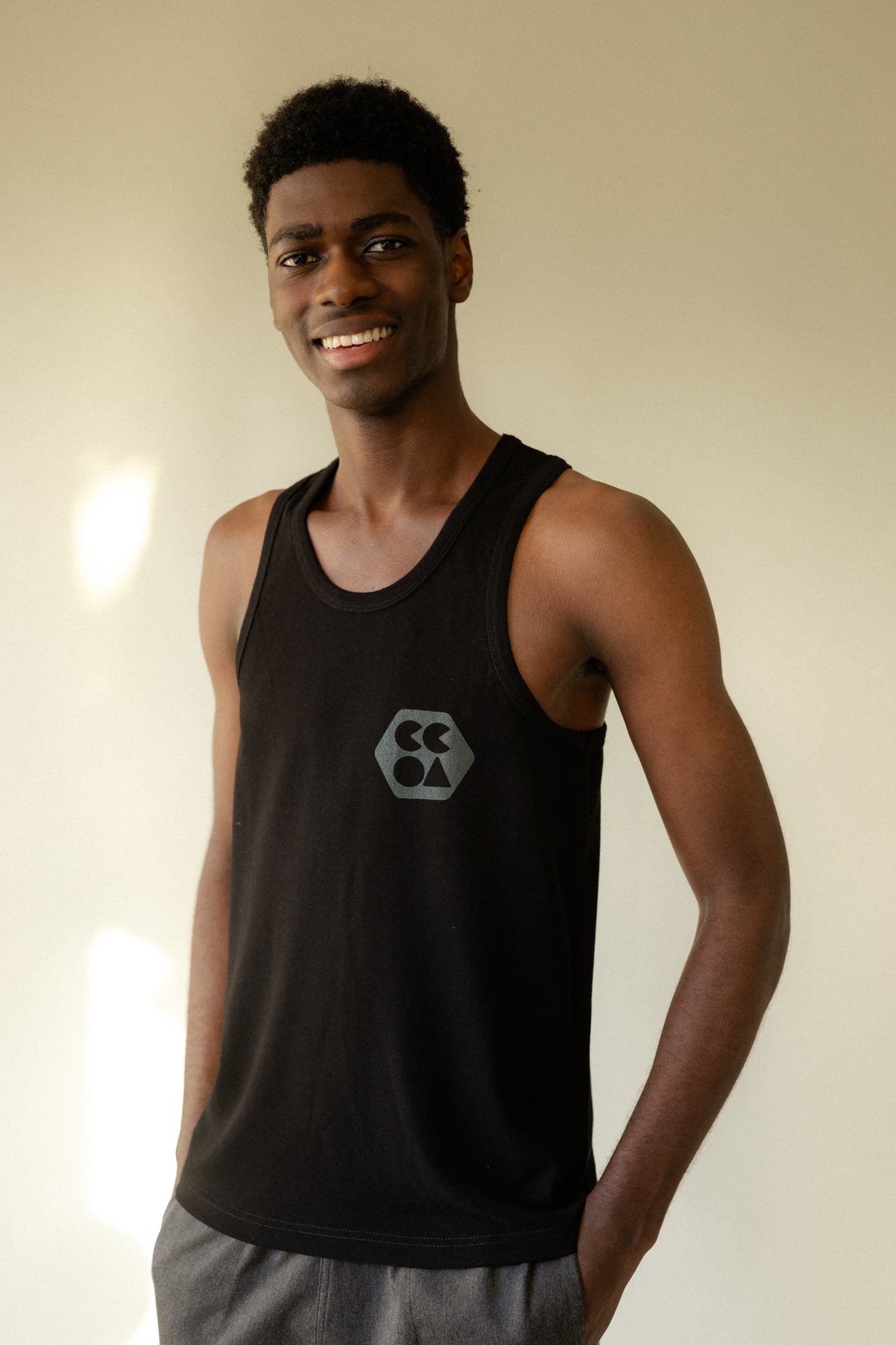 Smiley, male wearing breathable racer back vest plastic free in black with CCOA logo
