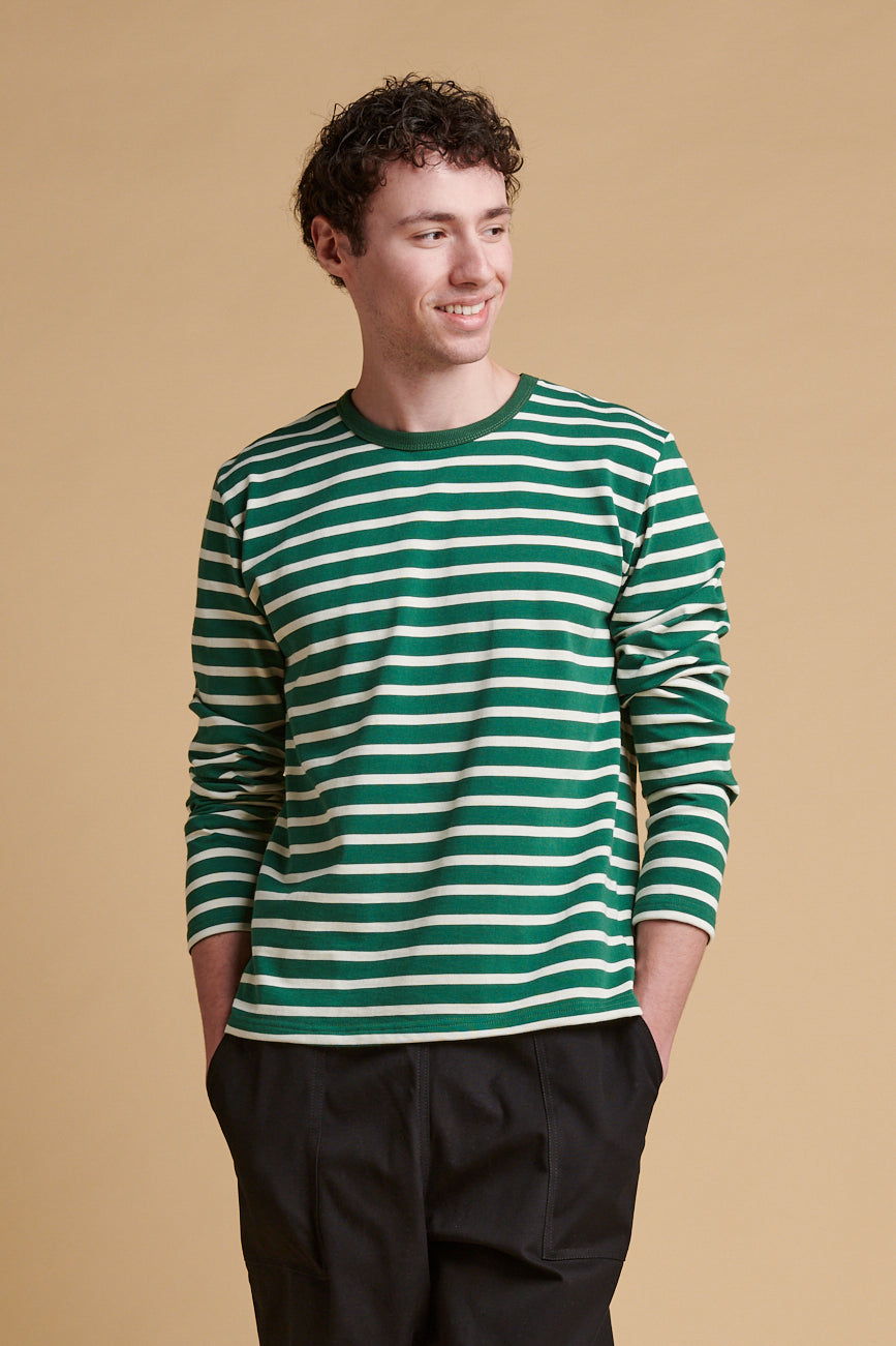 Thigh up front of smiley male wearing bottle green ecru stripe long sleeve Breton  top.