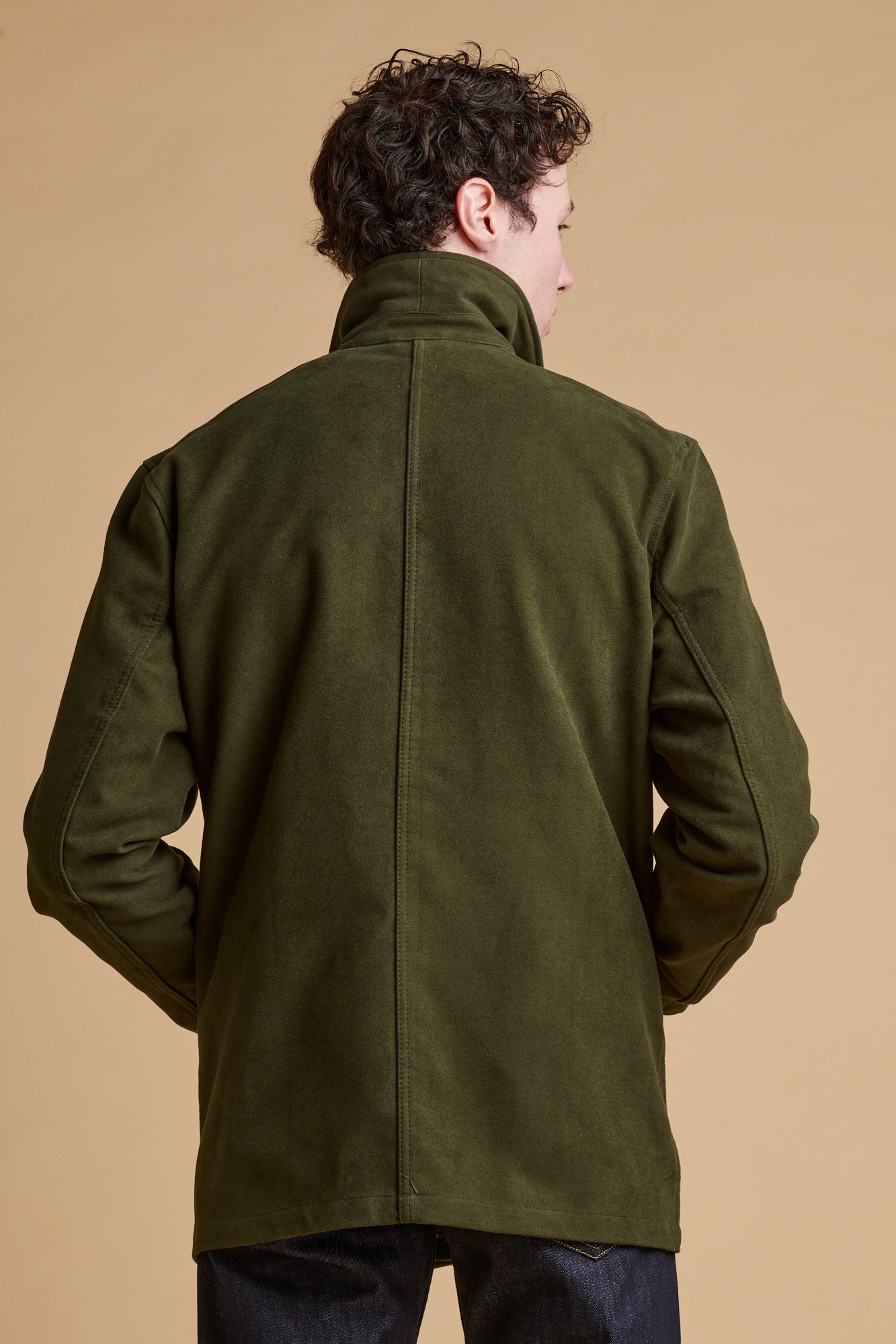 Male wearing Carter moleskin chore jacket in dark olive with collar turned up.