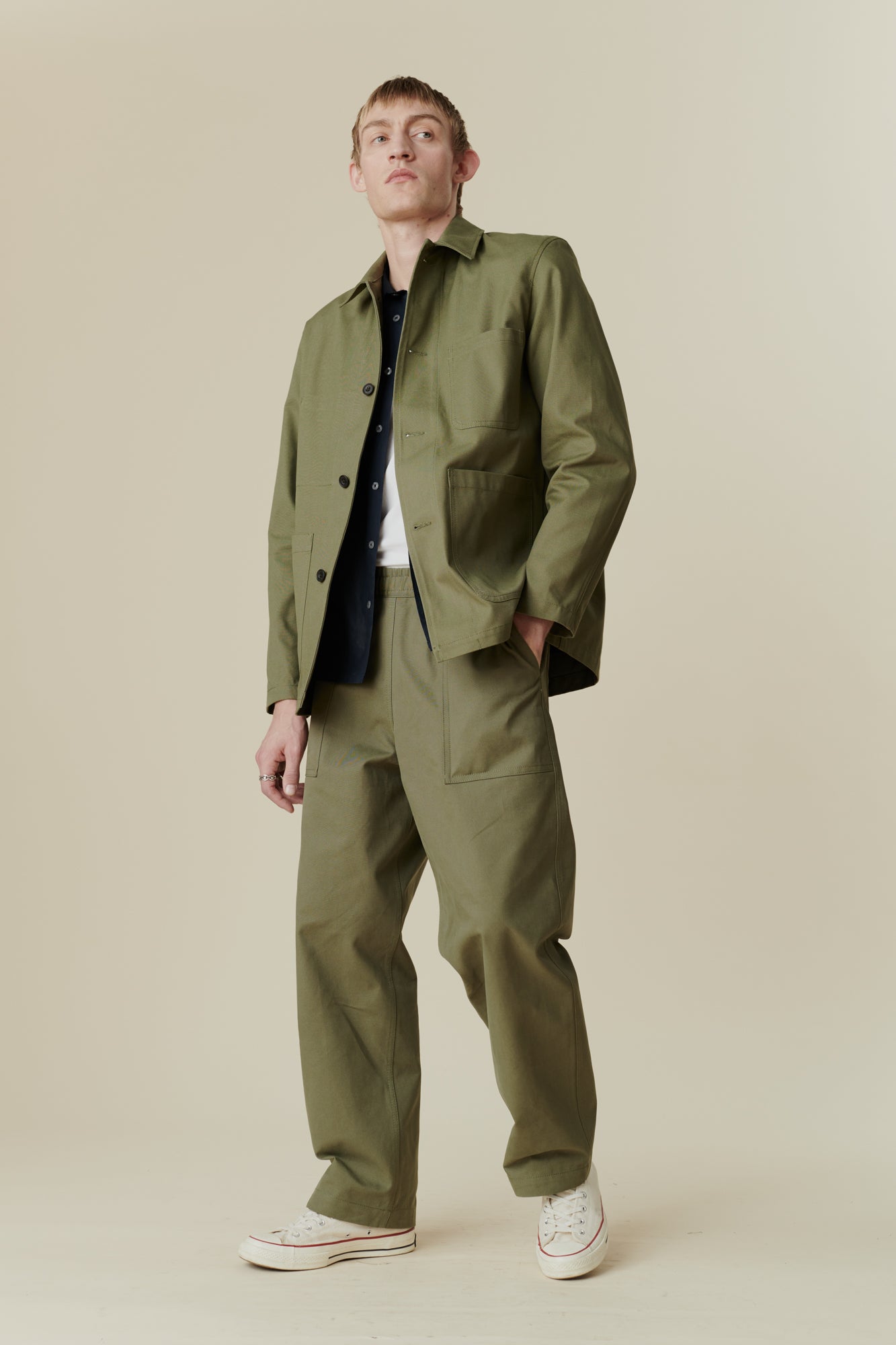 Full body image of white male wearing chore jacket in olive paired with chore jeans in olive