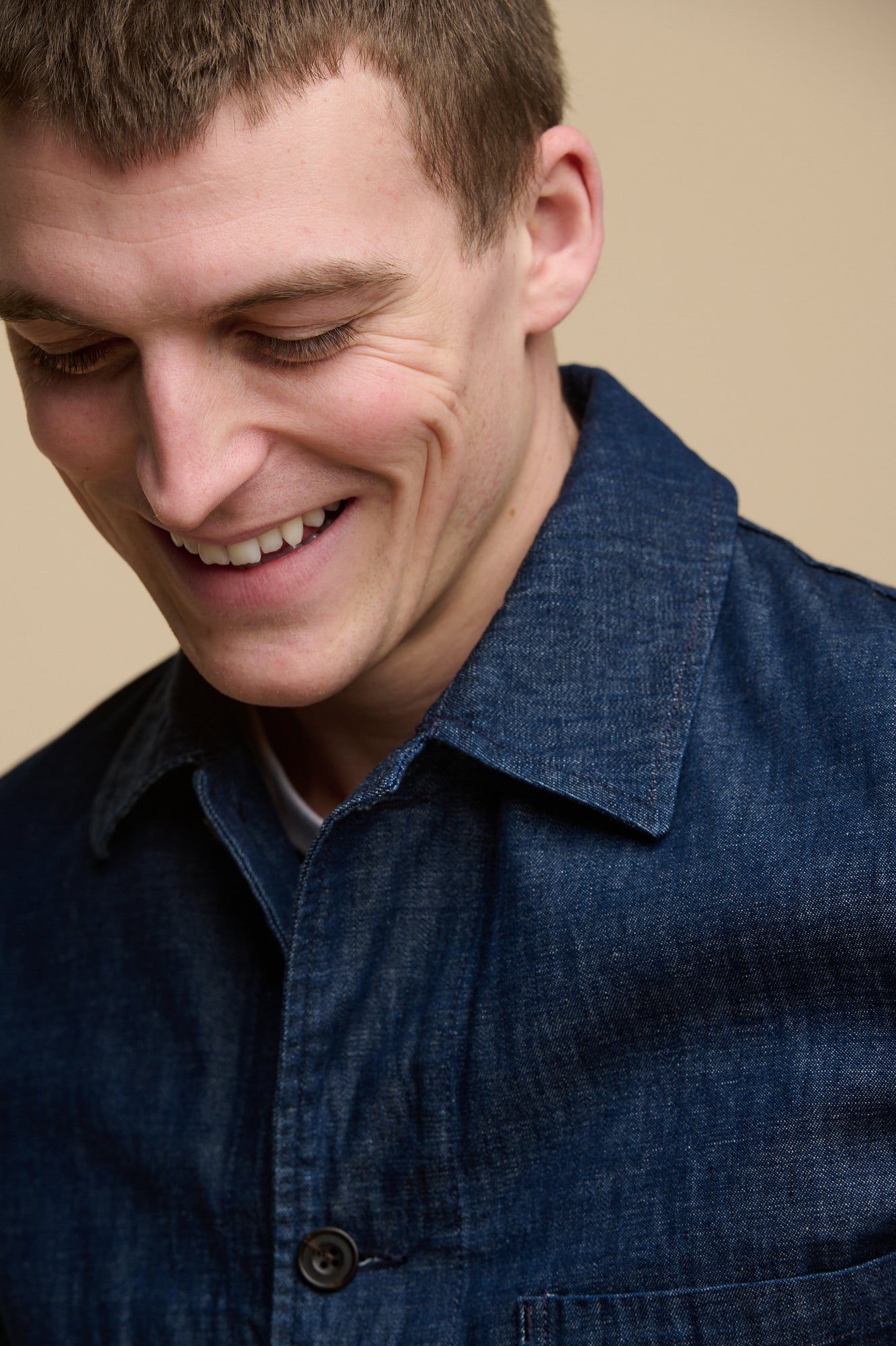 Thigh up image of male wearing chore jacket in denim over striped t-shirt.