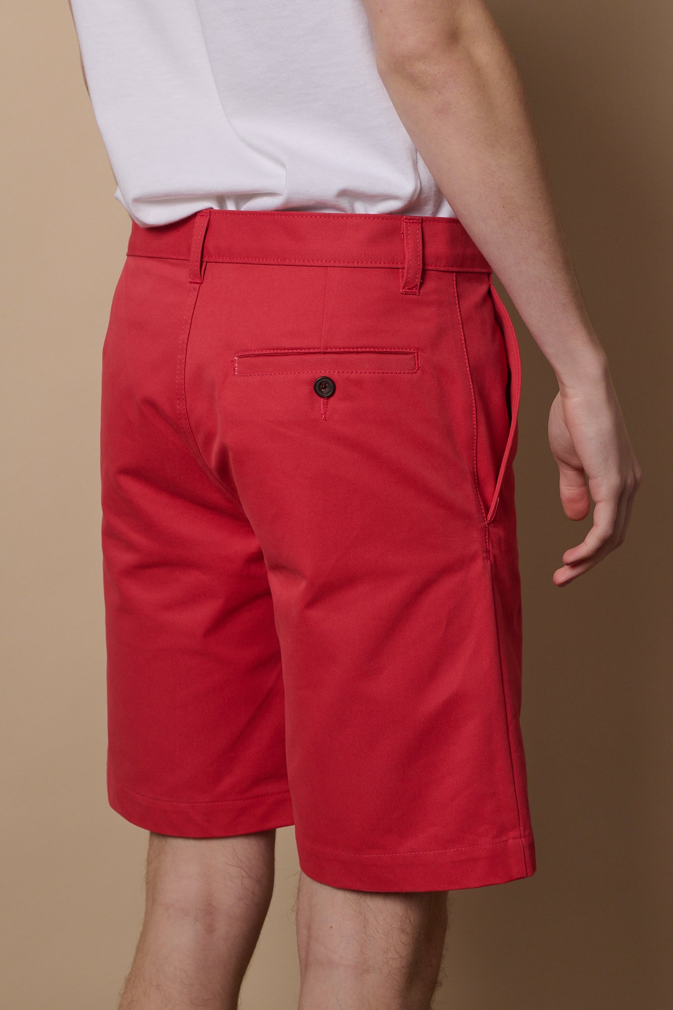 Full body image of white male wearing classic shorts in salmon blue paired with short sleeve white t shirt