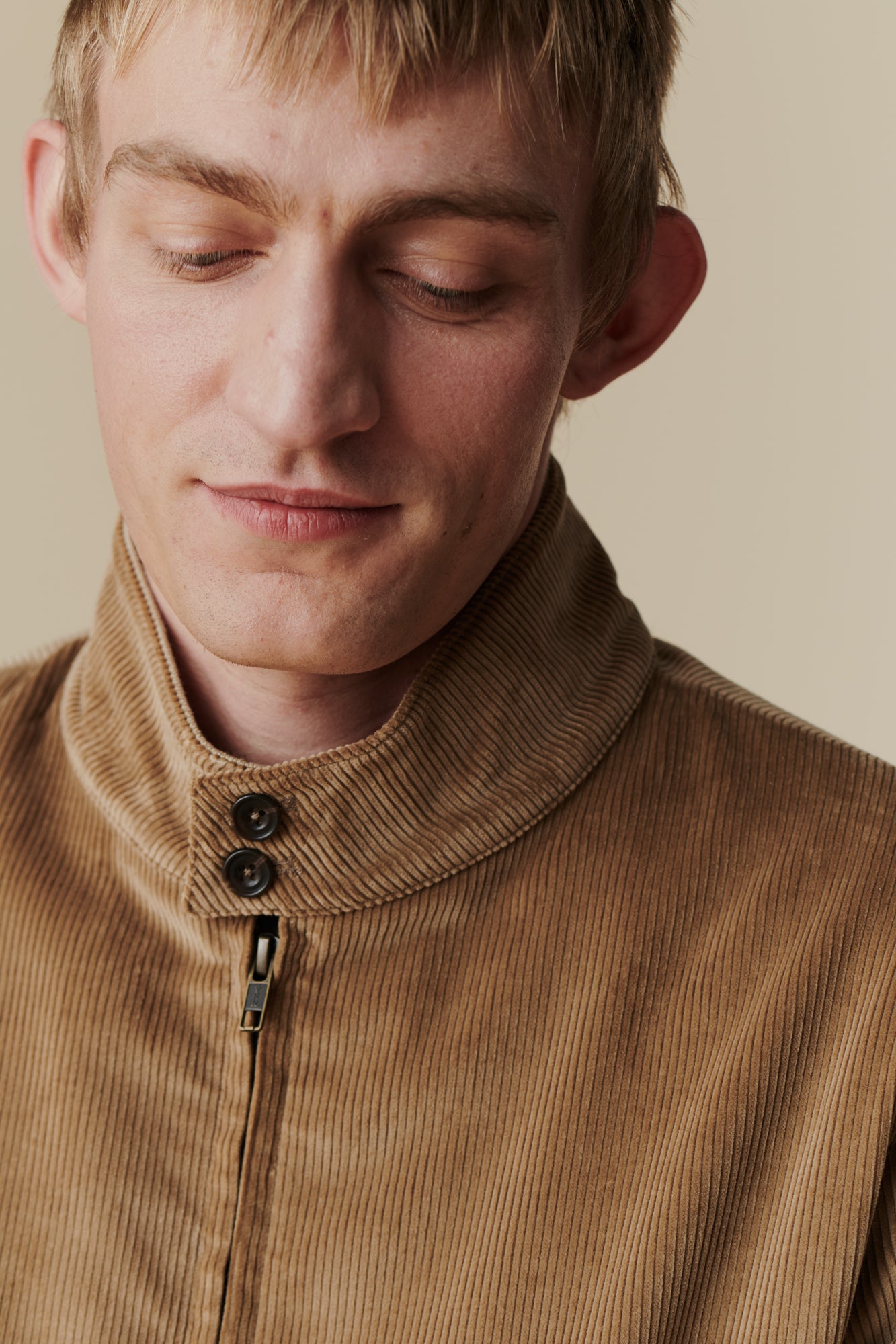 Portrait of white male wearing Blonde wearing men's corduroy Harrington jacket in stone
