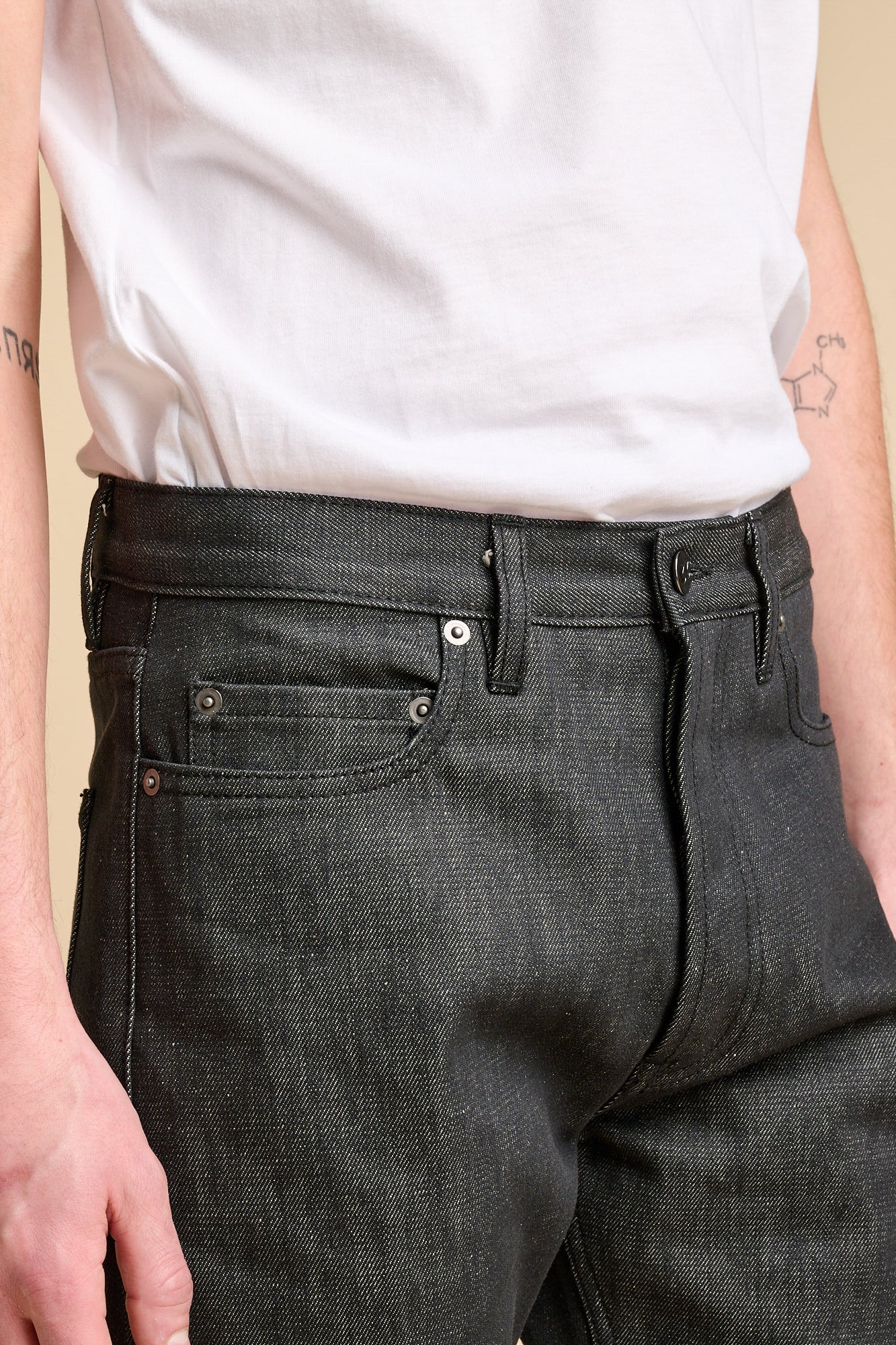Close up of man wearing black jeans with front pockets and belt loops.