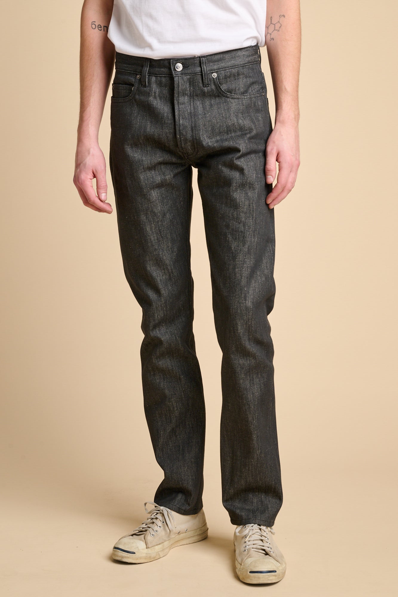 Man wearing black slim fit jeans with a white t shirt.