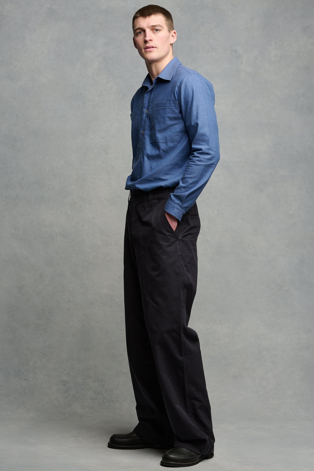 Full body image of the side of male wearing field trousers in navy paired with Oli half placket lightweight shirt in RAF Blue