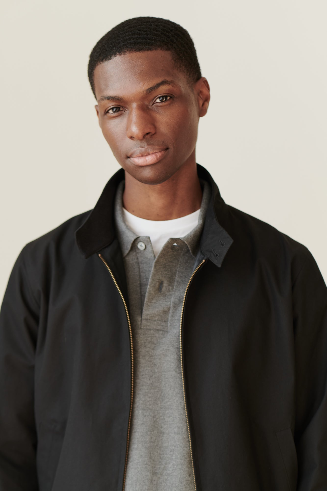 Portrait of black male wearing black Harrington jacket over grey long sleeve polo shirt
