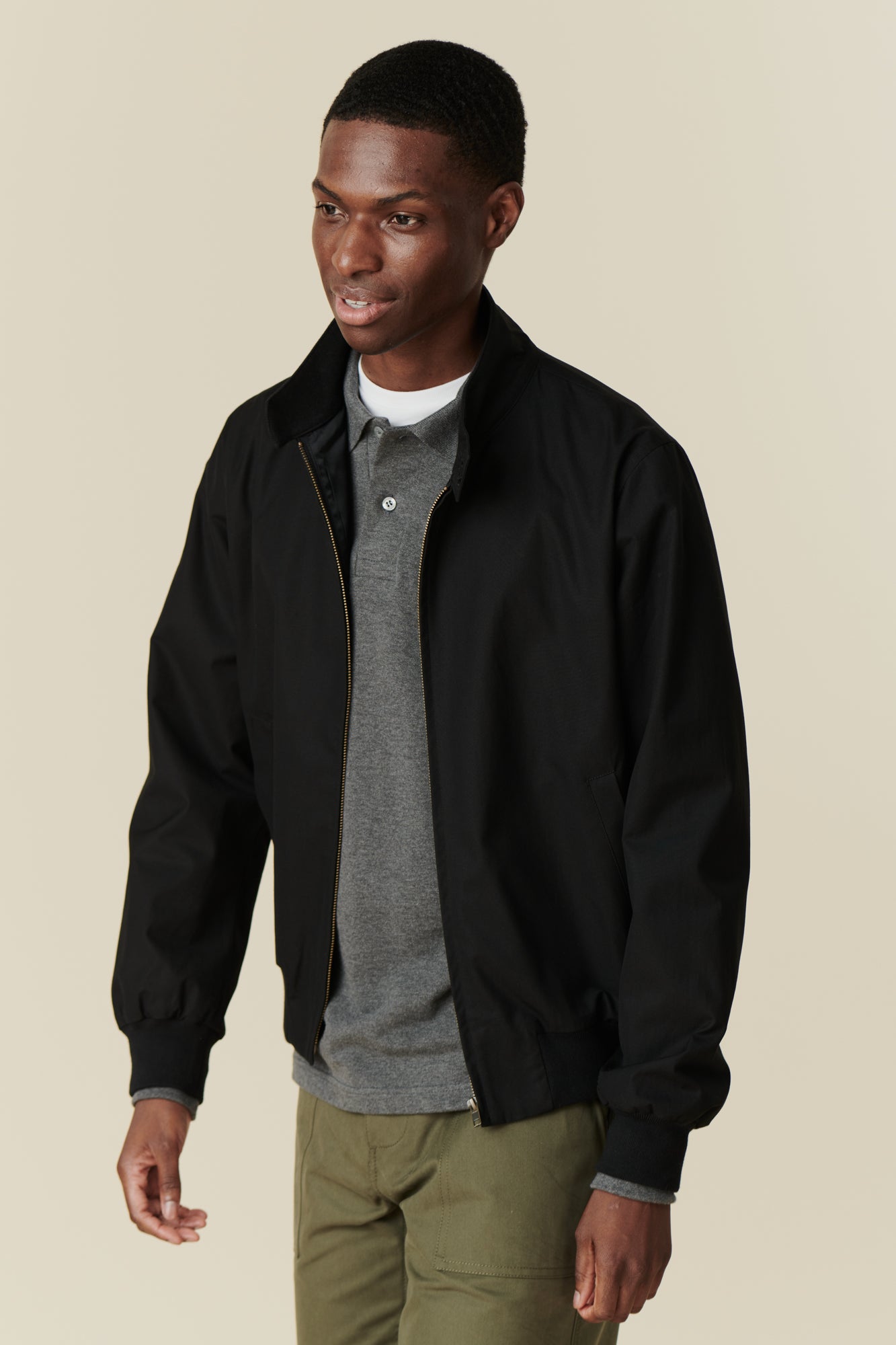 Front of black male wearing black Harrington jacket over grey long sleeve polo