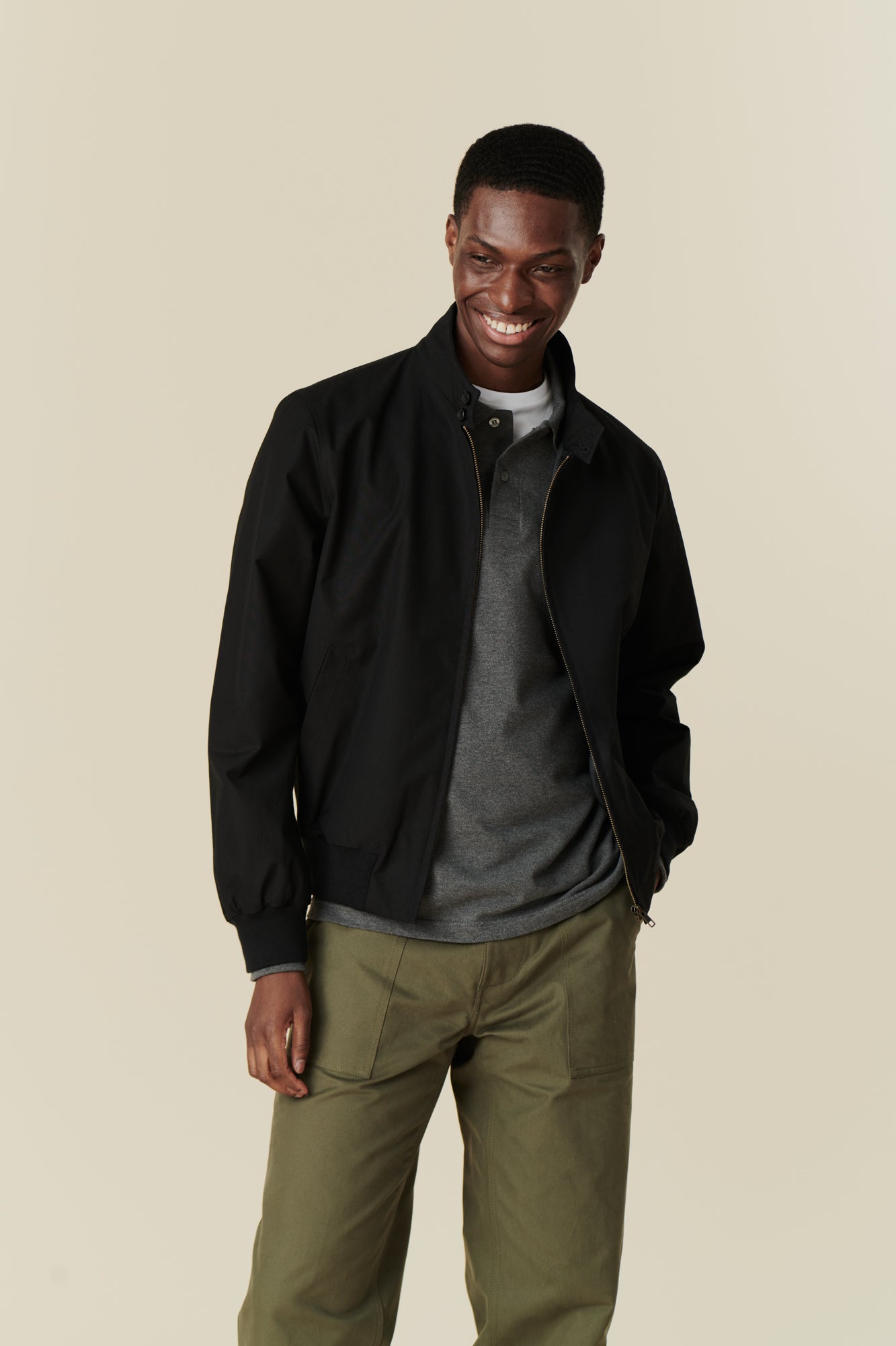 Front of smiley black male wearing black Harrington jacket over grey long sleeve polo