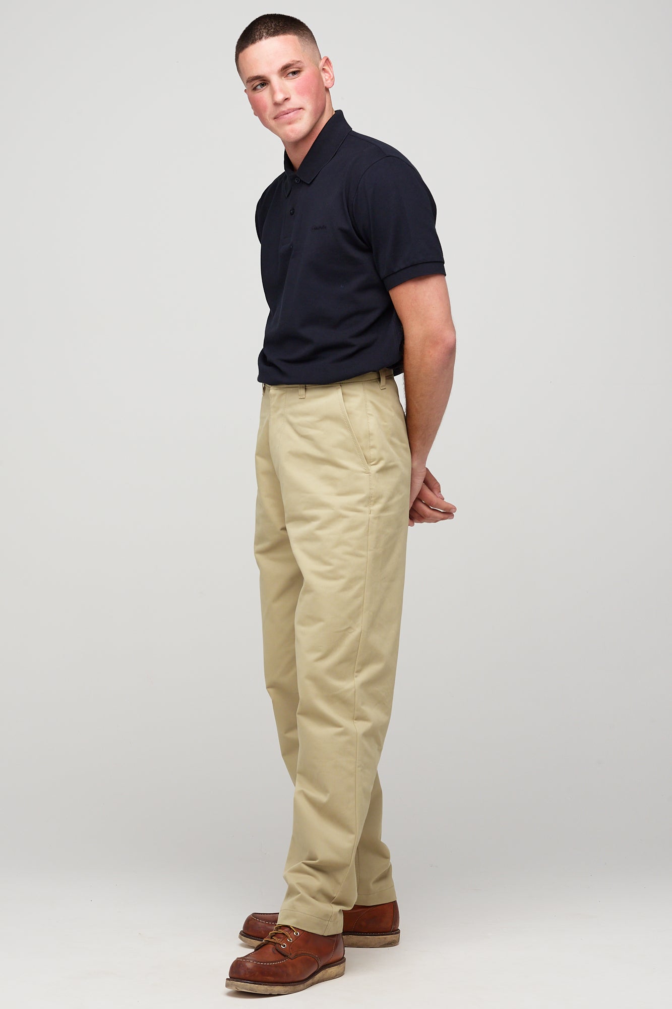 White, brunette male in stone heavyweight relaxed chino styled with navy short sleeve polo shirt 