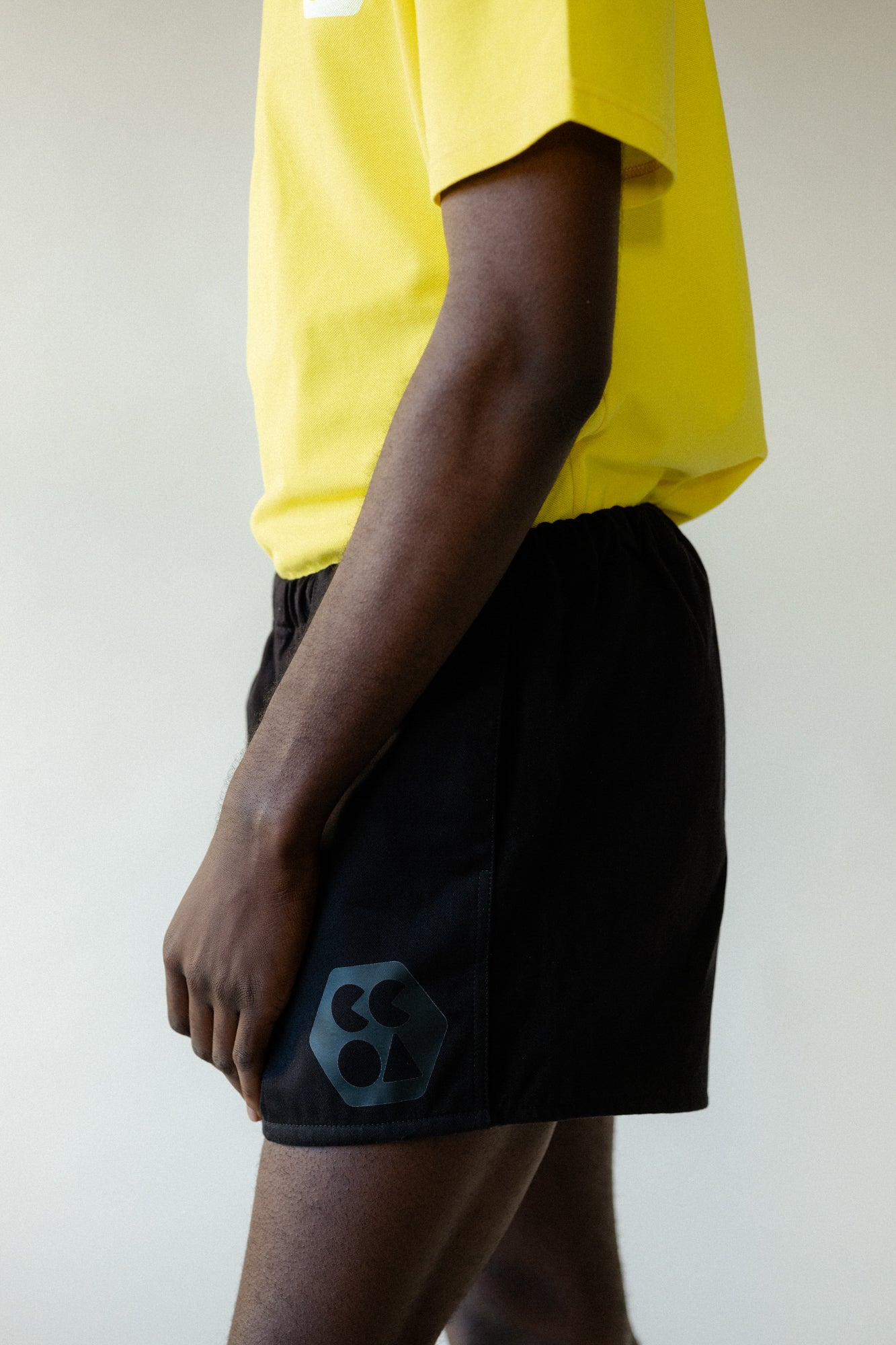 Image showing the side of black male chest to knee wearing men's heavyweight sports short plastic free in black with CCOA logo