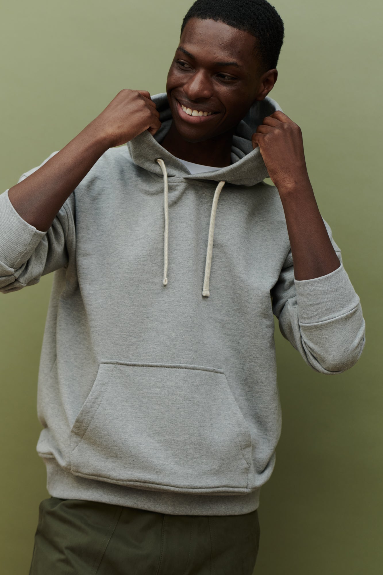 Thigh up image of black male wearing hooded sweatshirt in grey with one front pocket