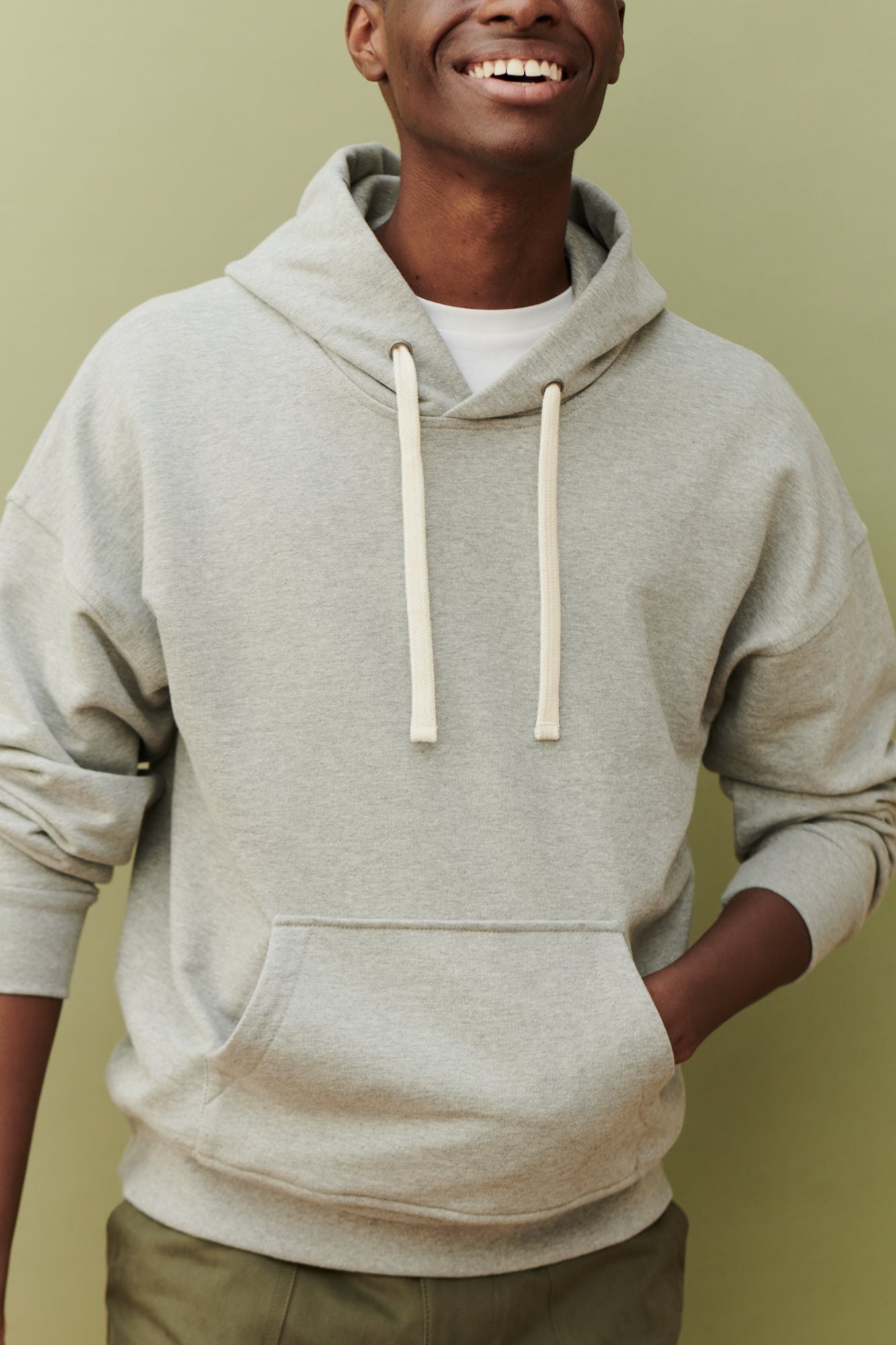 Thigh up image of black male wearing hooded sweatshirt in grey with one front pocket