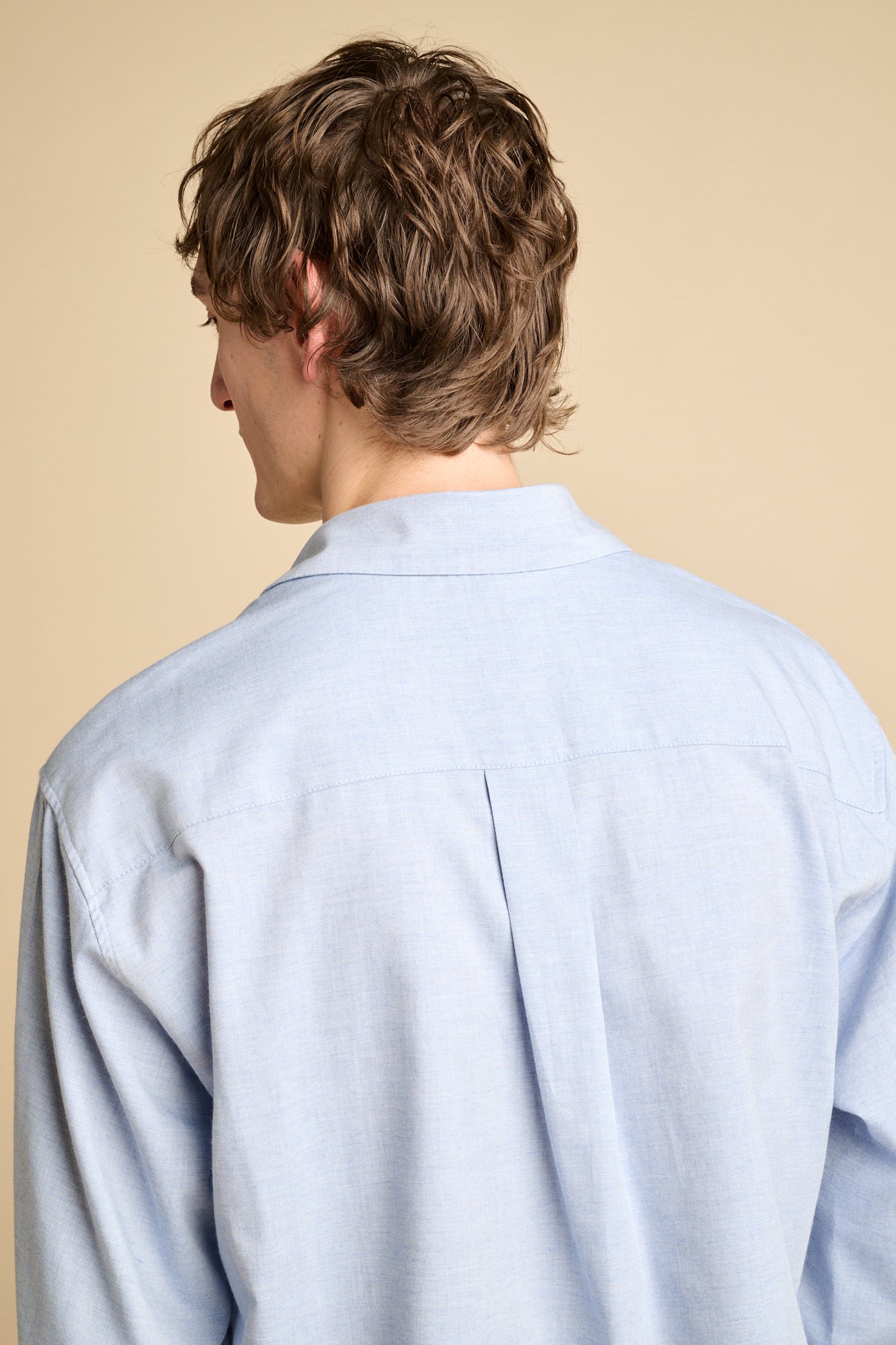 The back of a man wearing long sleeve light blue shirt.