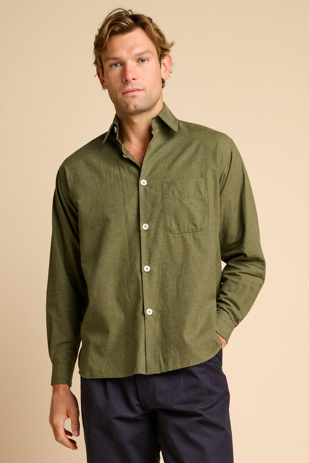 Man wearing green shirt against beige background. 