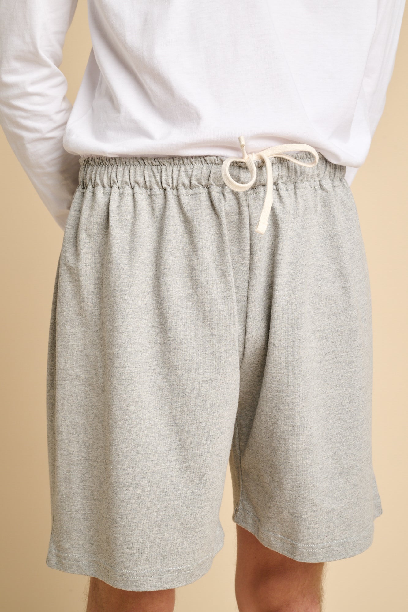 Man wearing grey marl jersey shorts with ecru drawcord.