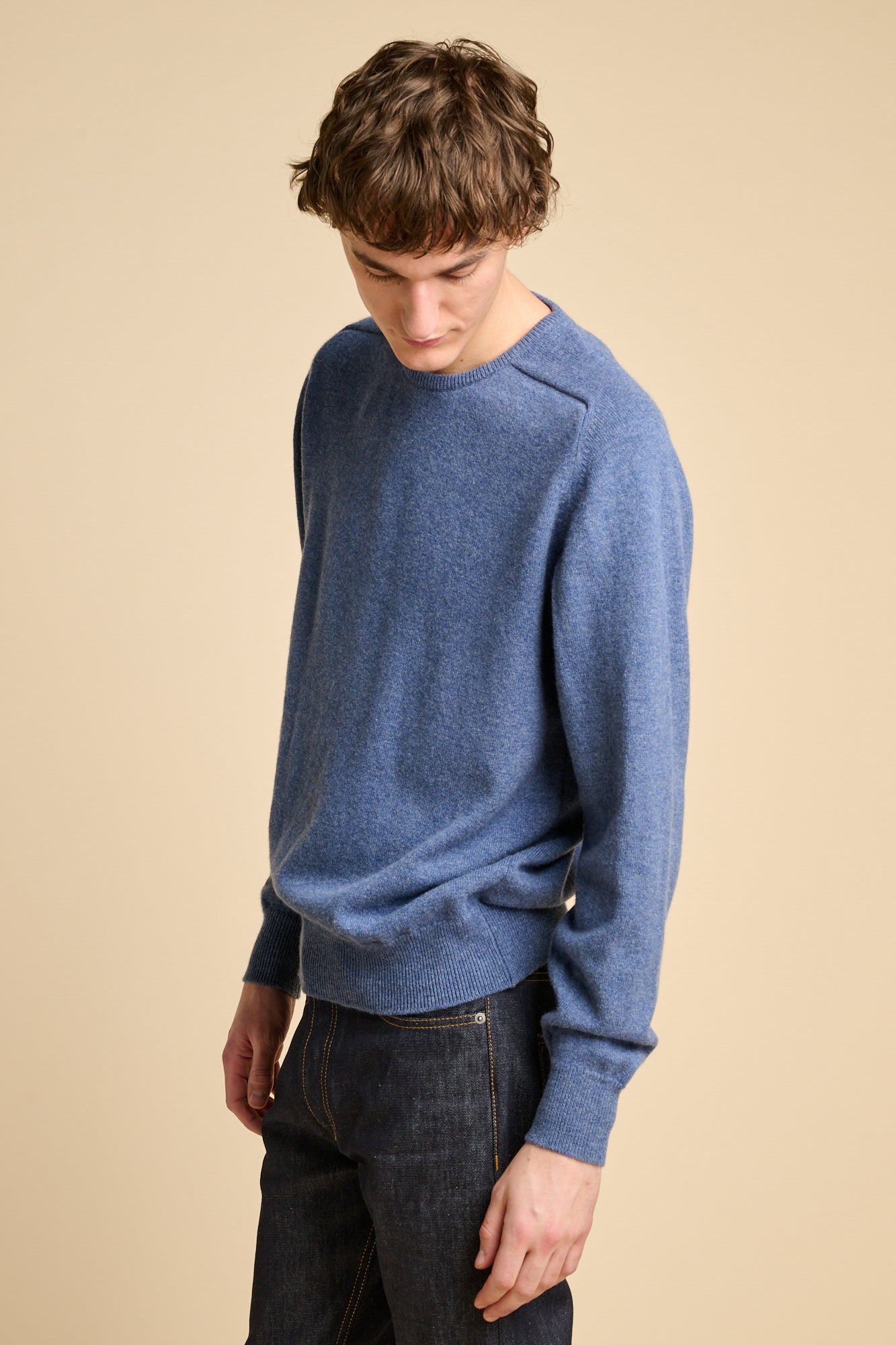 Man wearing lambswool saddle shoulder crew neck in denim blue.