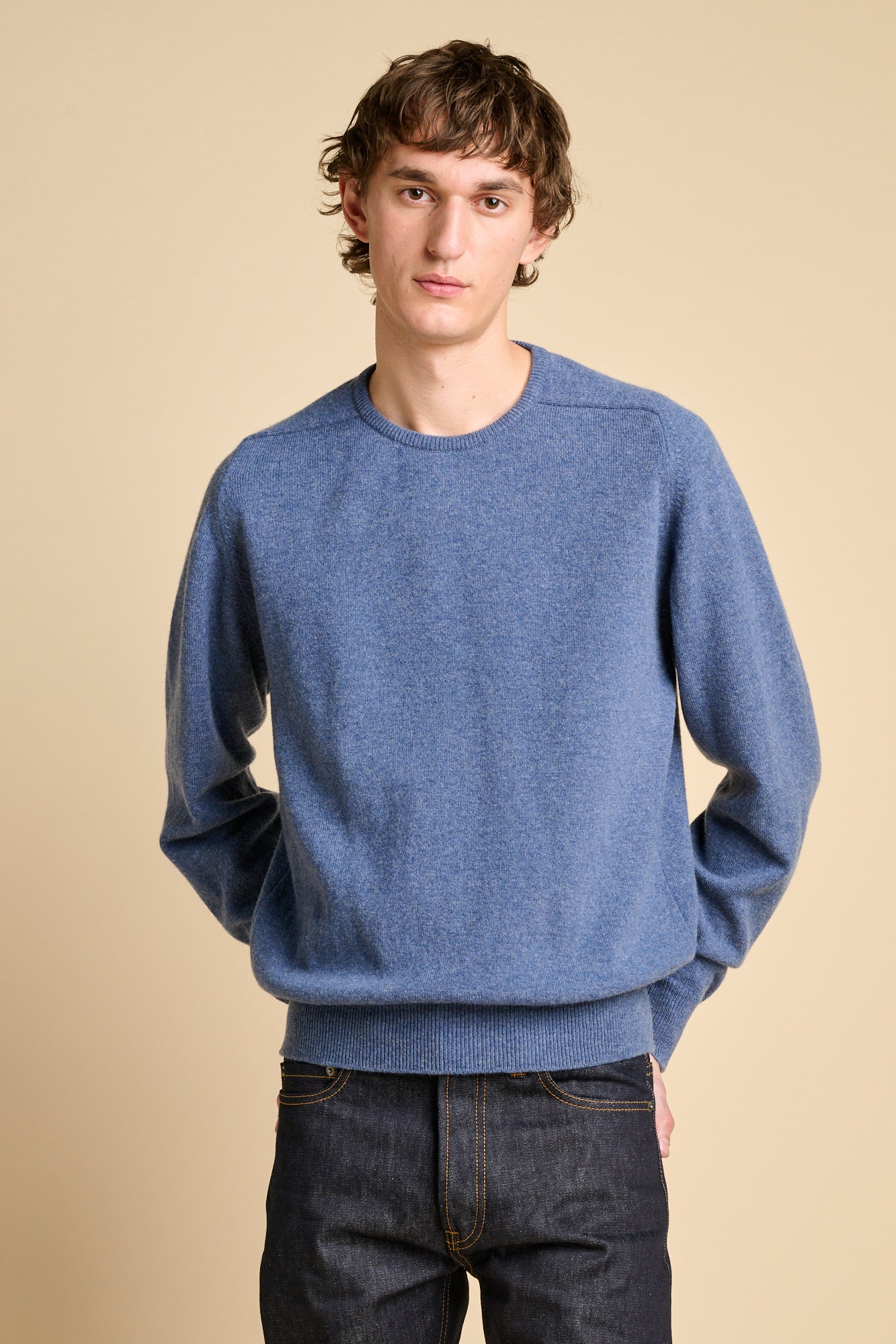 Man wearing lambswool saddle shoulder crew neck in denim blue.