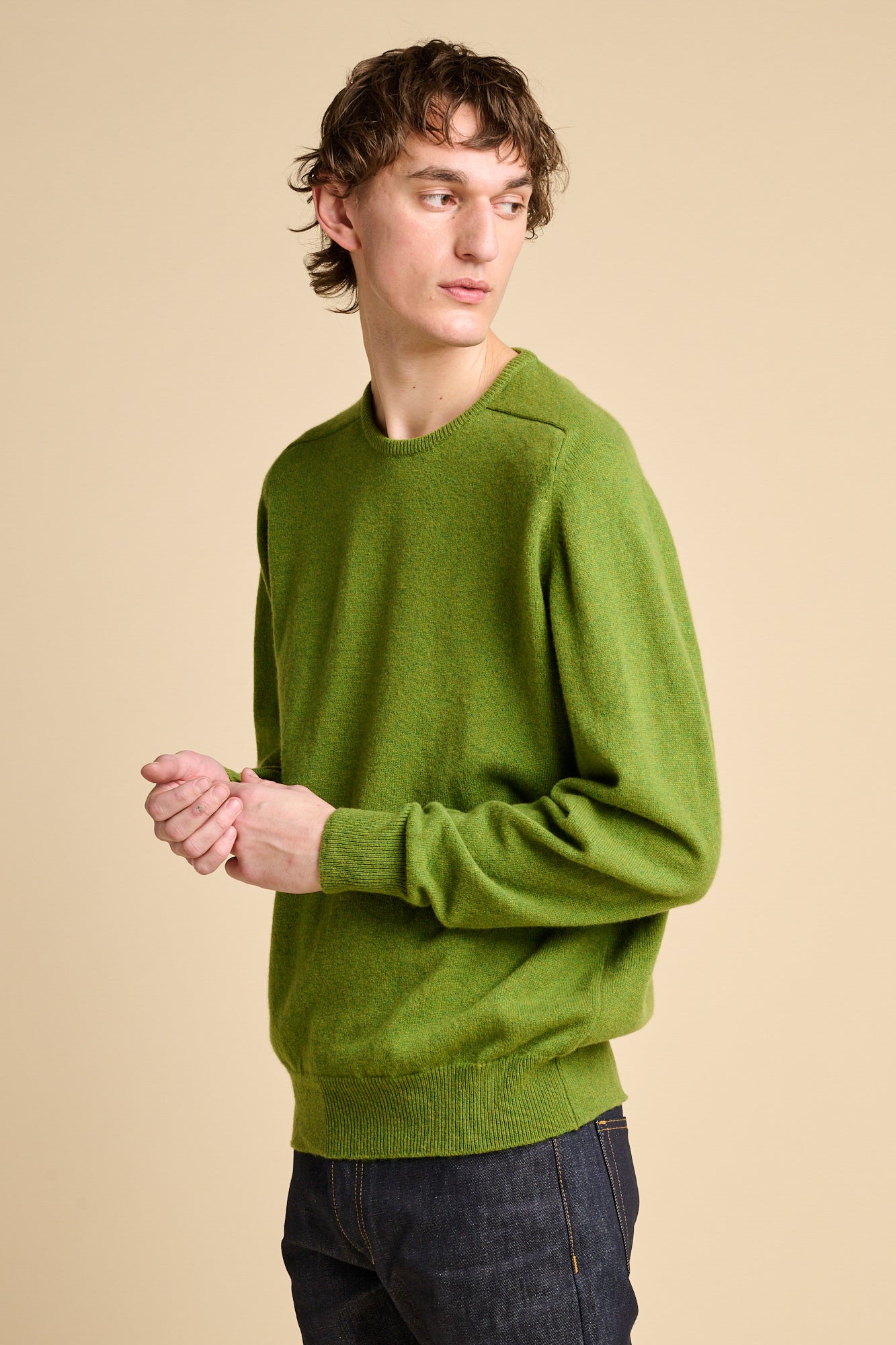 Man wearing lambswool saddle shoulder crew neck jumper in moss green.