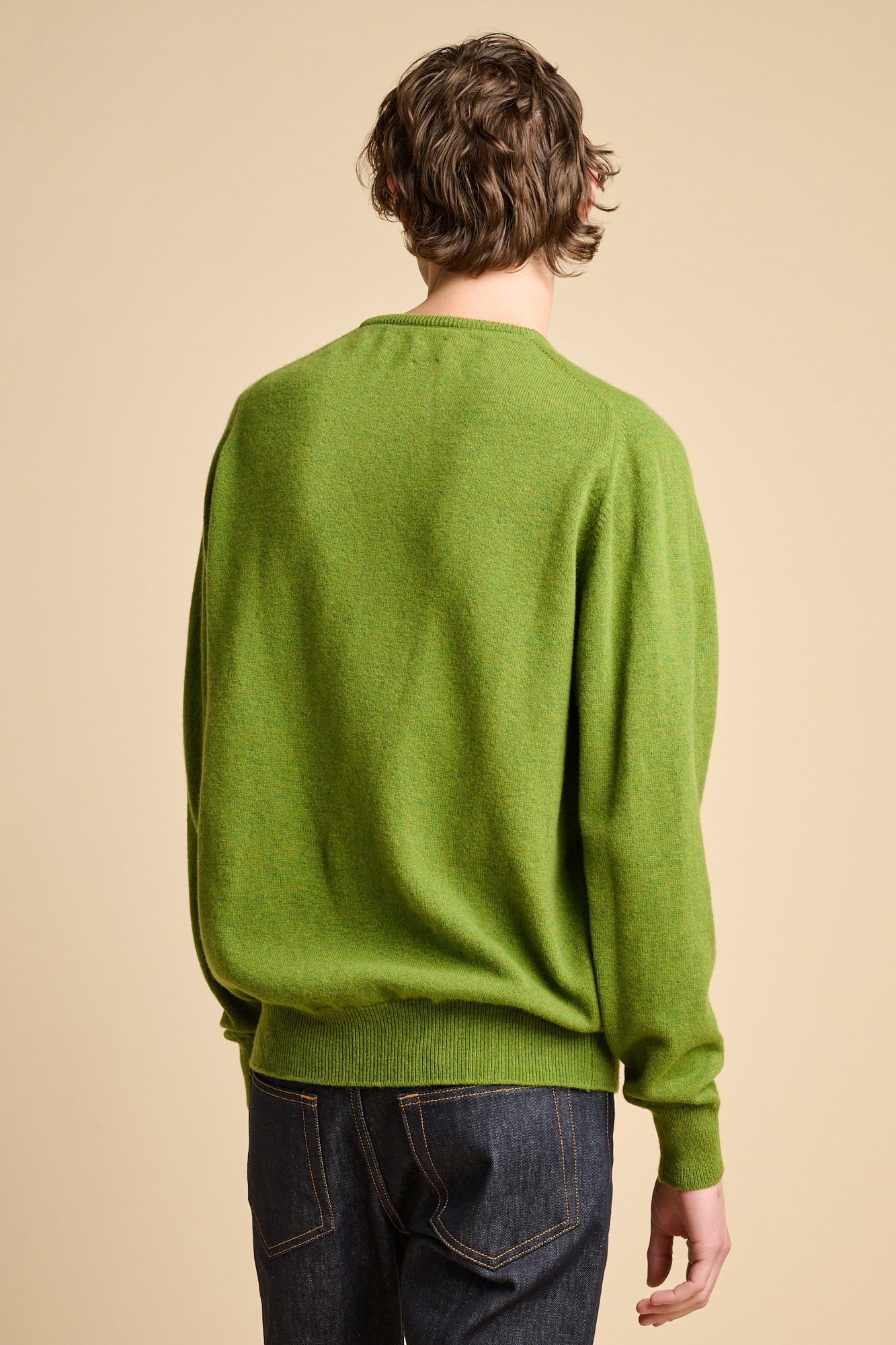 The back of man wearing lambswool saddle shoulder crew neck jumper in moss green.
