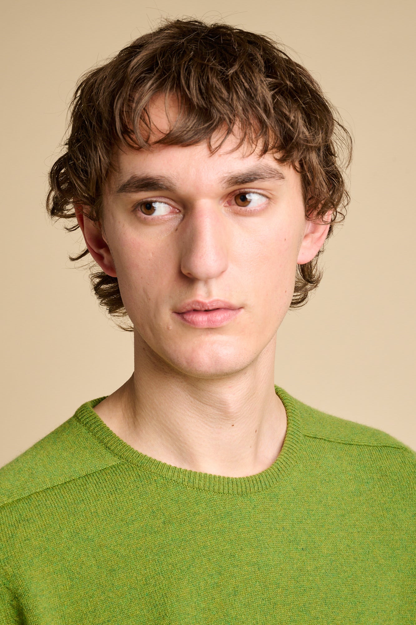 Portrait of male wearing wearing lambswool saddle shoulder crew neck jumper in moss green.