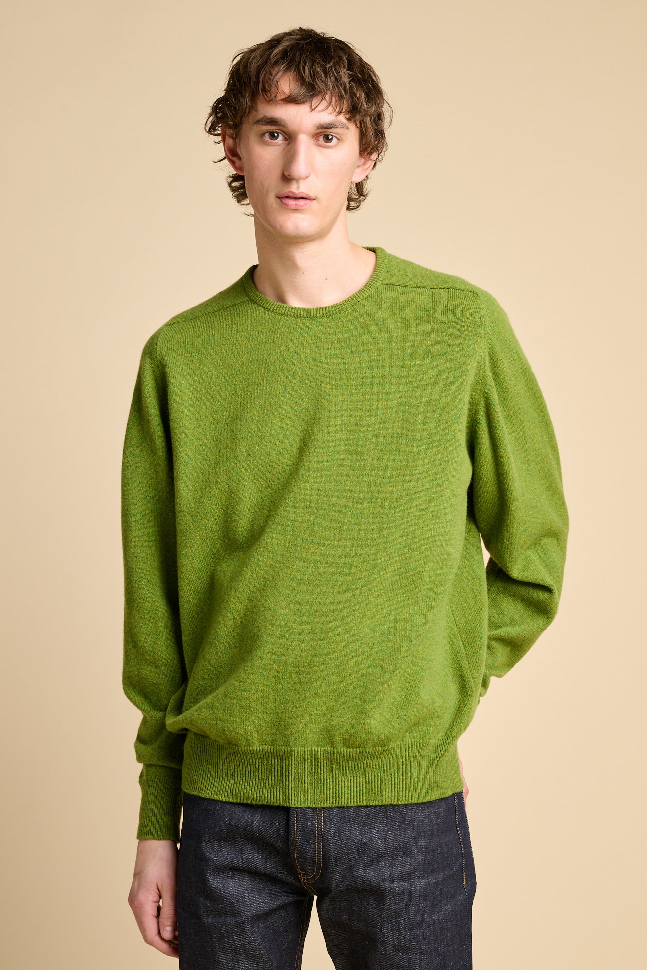 Man wearing lambswool saddle shoulder crew neck jumper in moss green.