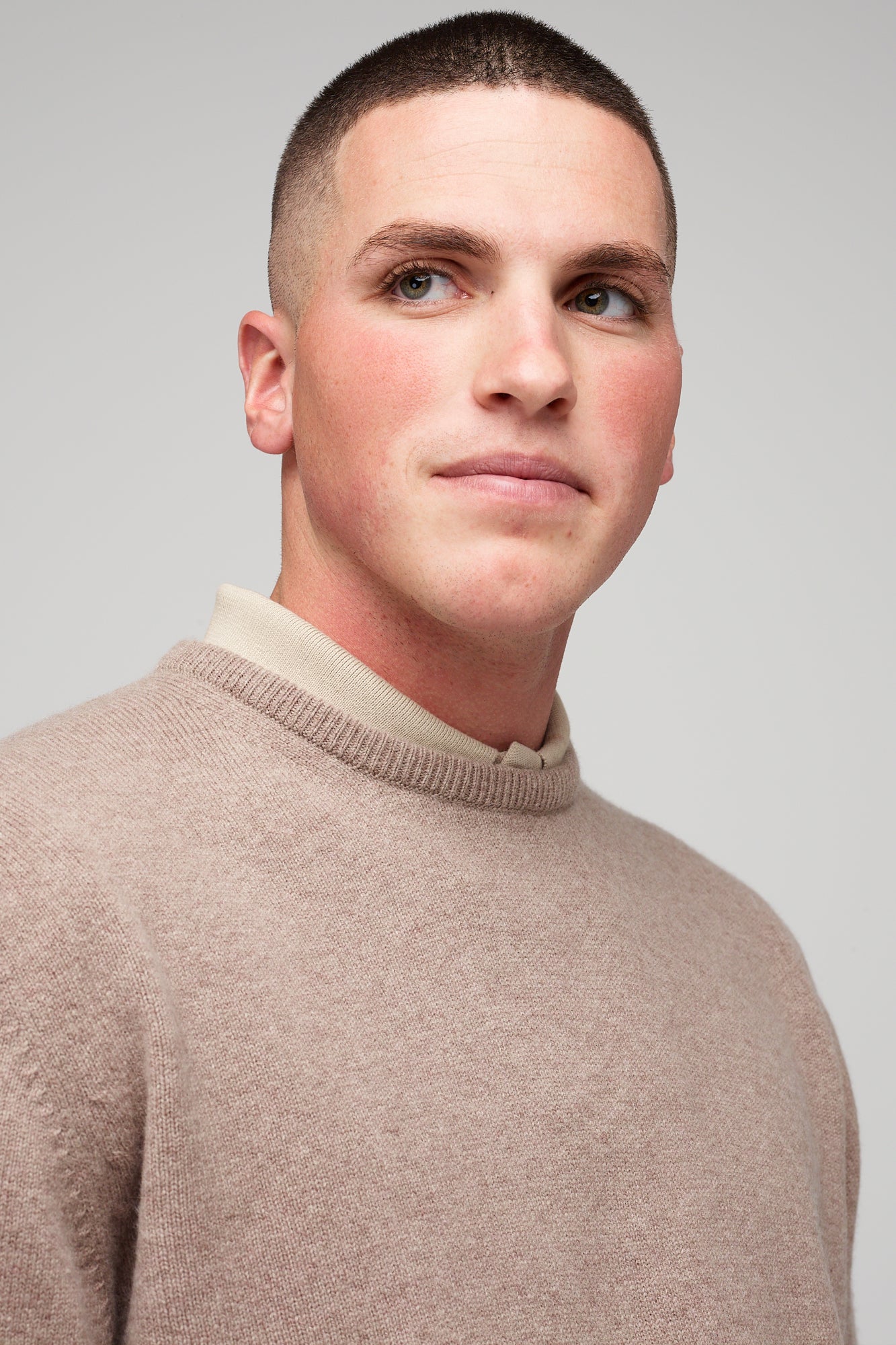 brunette, white male in taupe lambswool crew neck, styled over short sleeve polo in stone