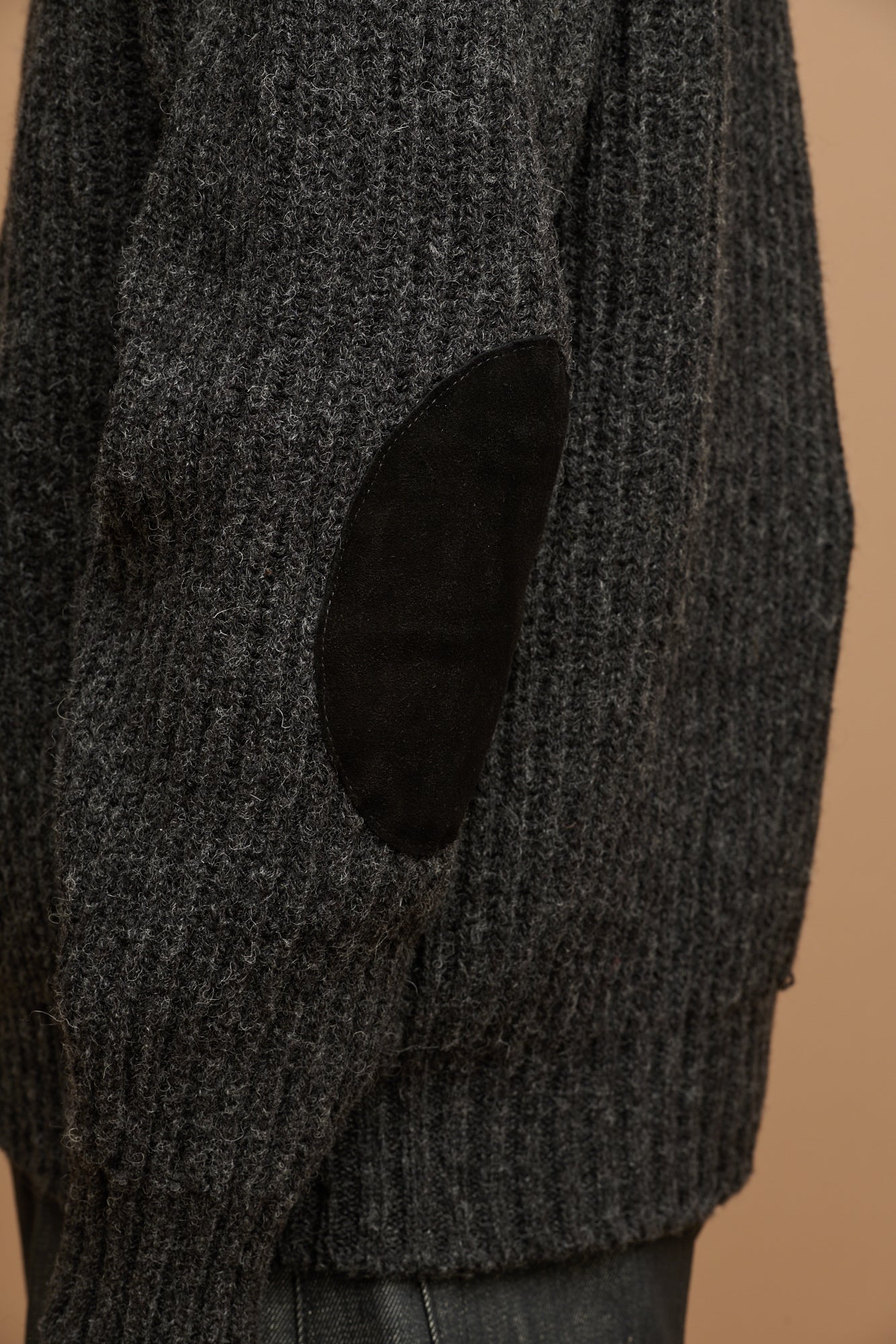 Close up of the side of lambswool fisherman ribbed jumper in charcoal showing suede elbow patch 