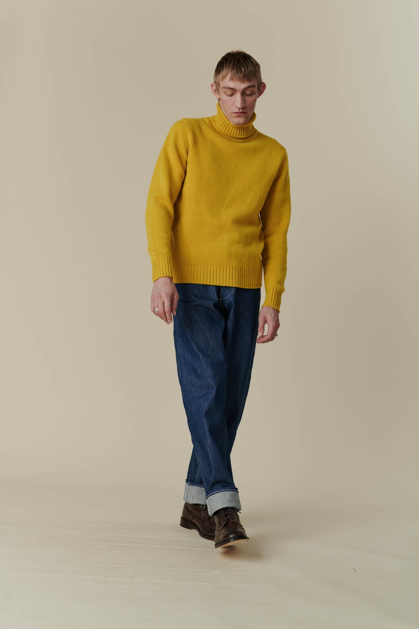 Thigh up image of white male in mustard lambswool roll neck 