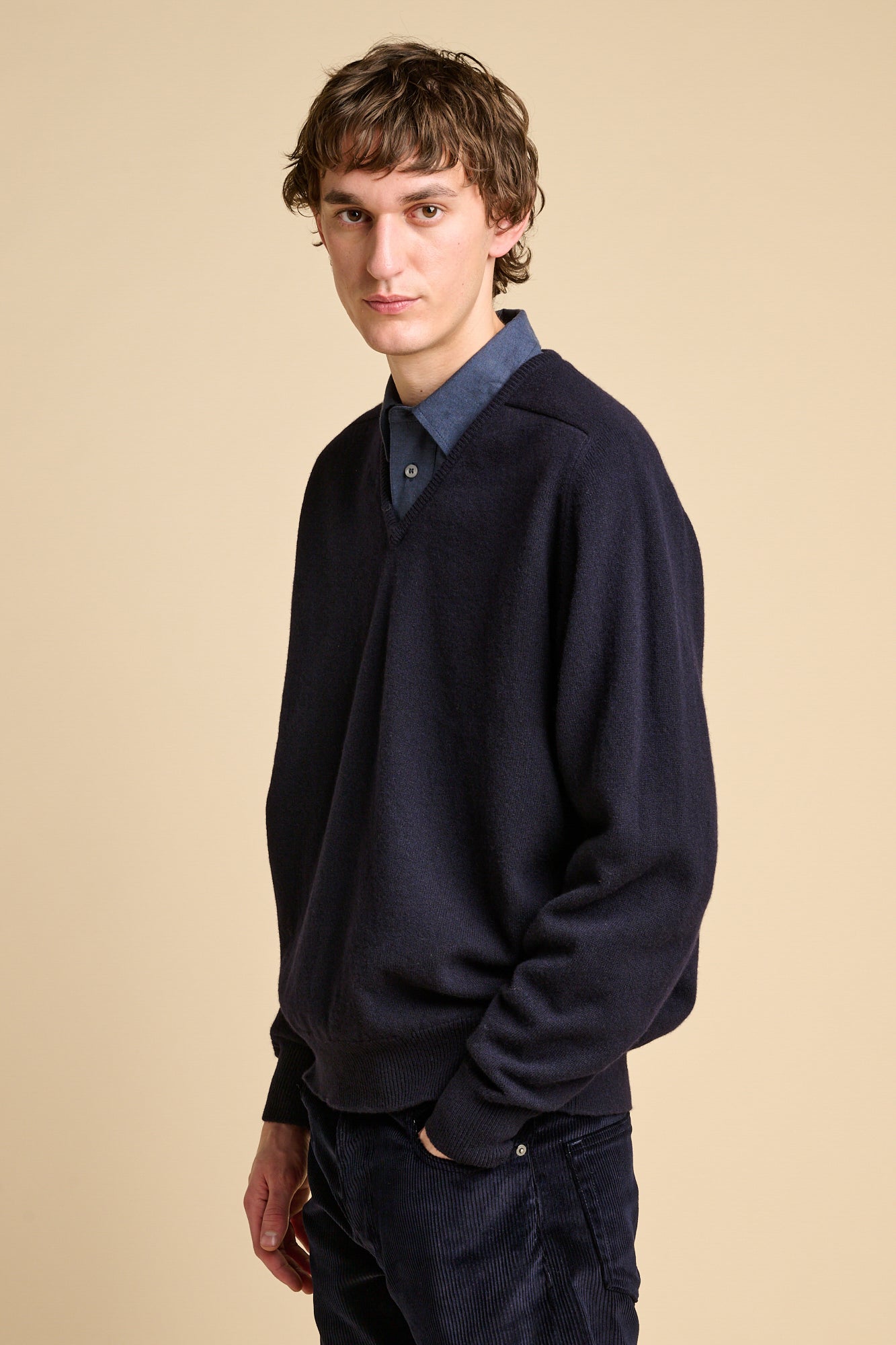 Man wearing lambswool v neck jumper in navy 