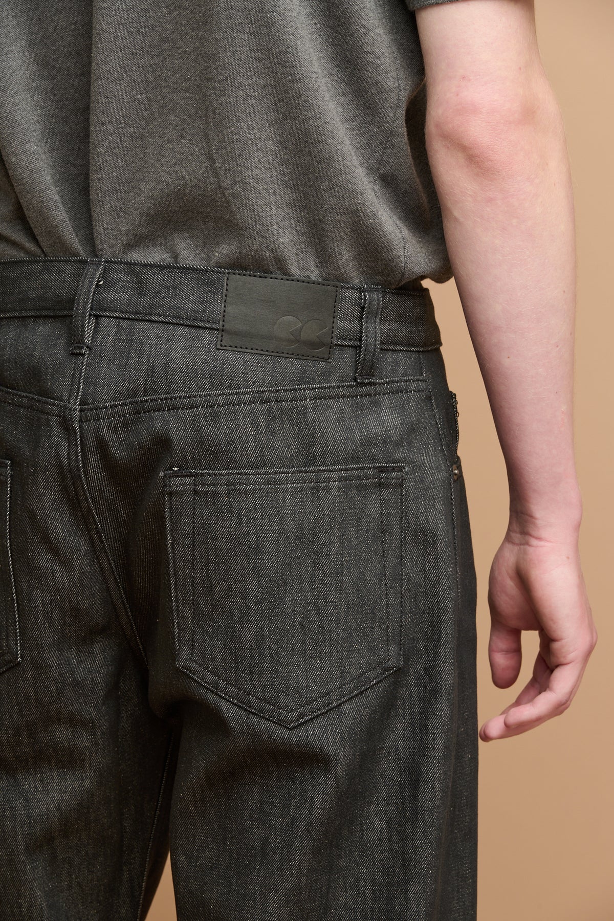 Close up of the back of button fly arran jean in black with black jeans patch on waistband