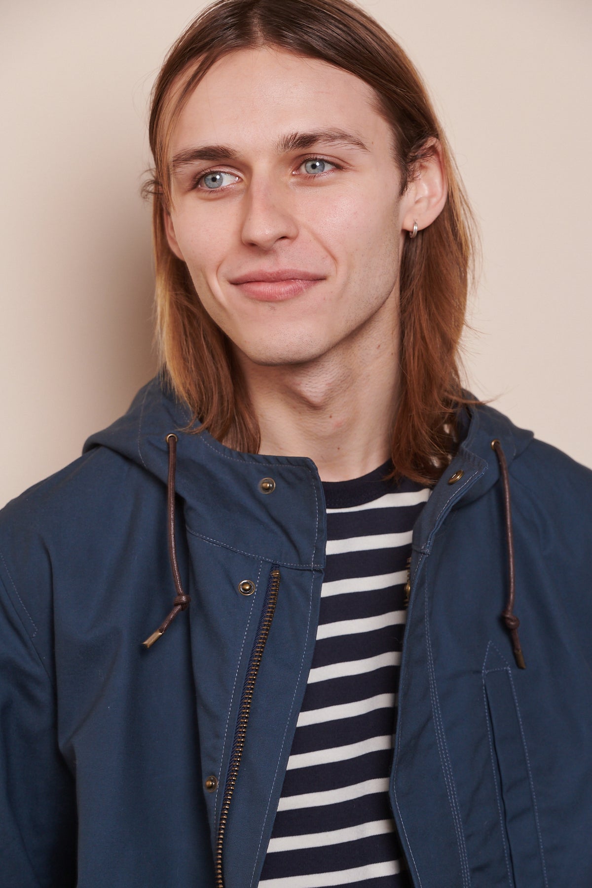 Portrait of smirking male wearing Mountain Parka in navy over navy ecru breton. 