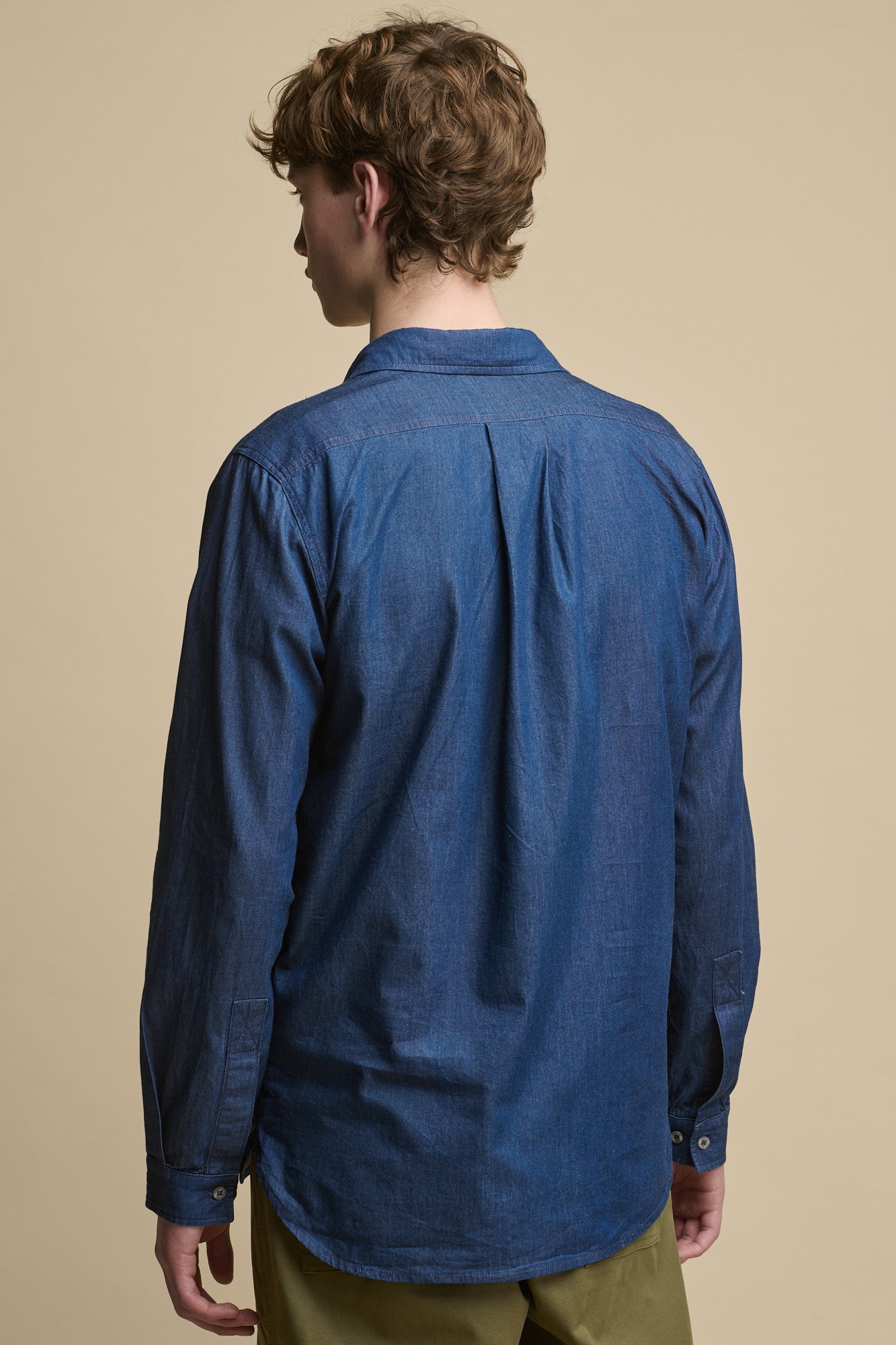 Thigh up image of the back of male wearing Oli Half Placket Lightweight Denim Shirt in indigo 