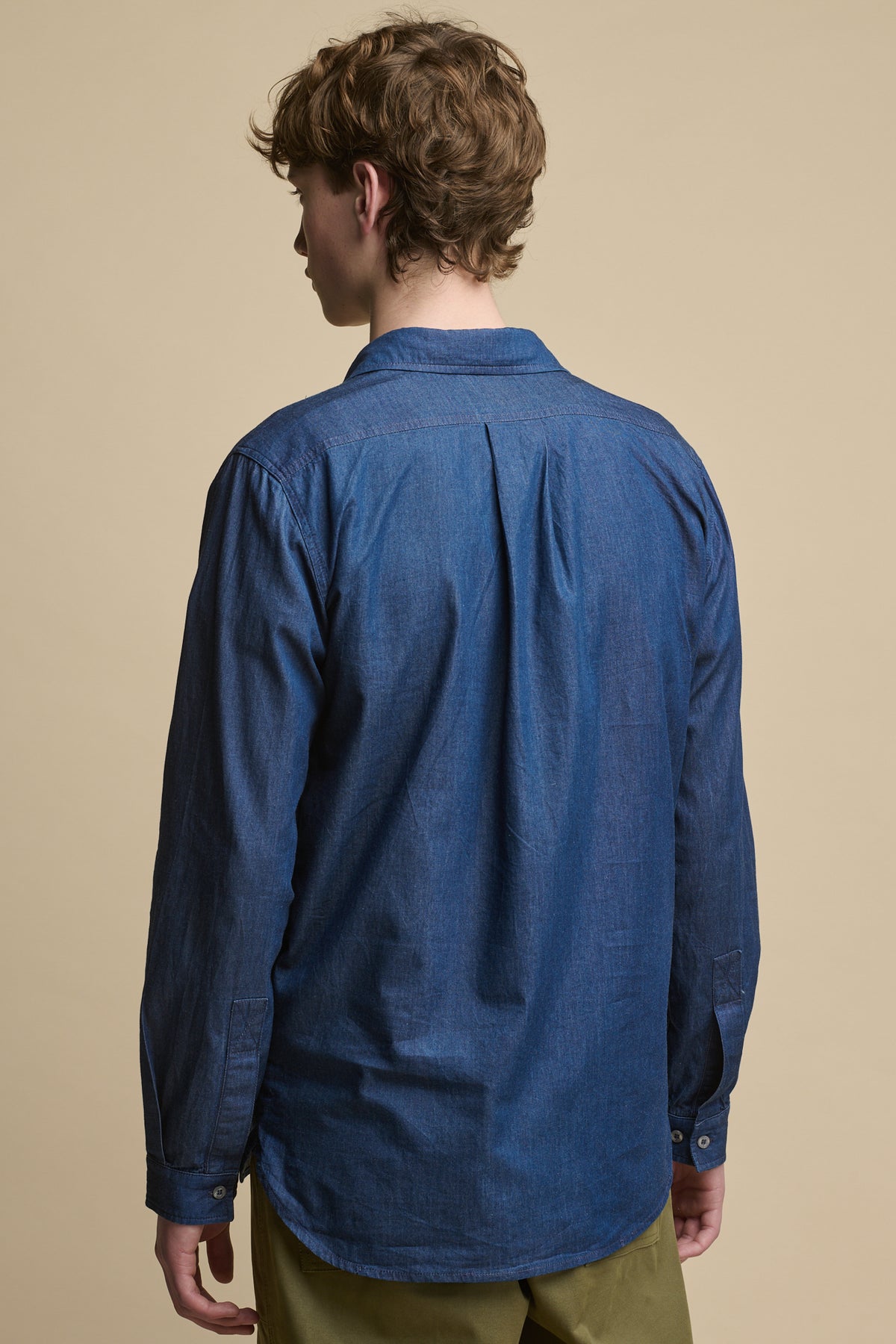 Thigh up image of the back of male wearing Oli Half Placket Lightweight Denim Shirt in indigo 