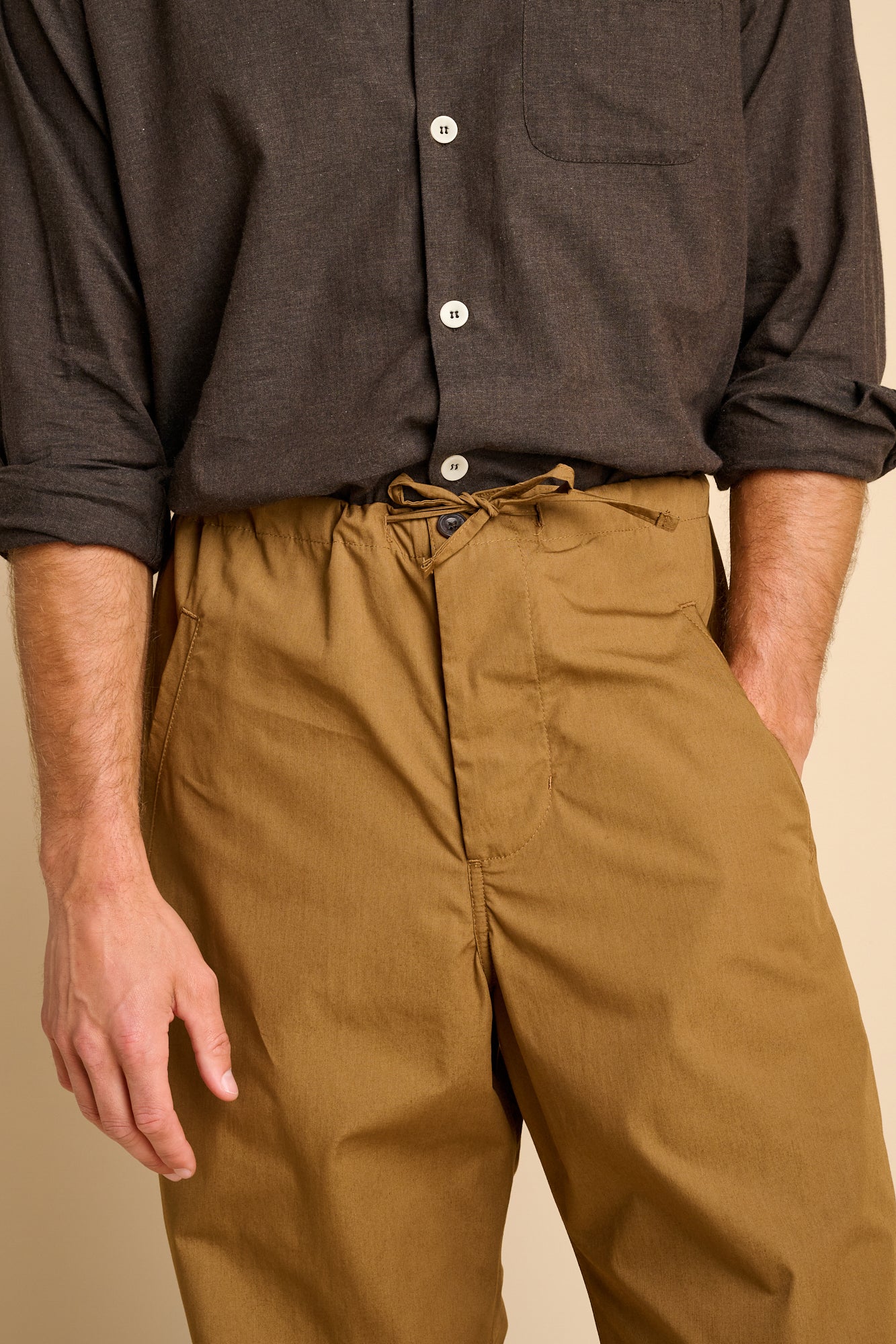 Man wearing tan trousers with brown shirt.