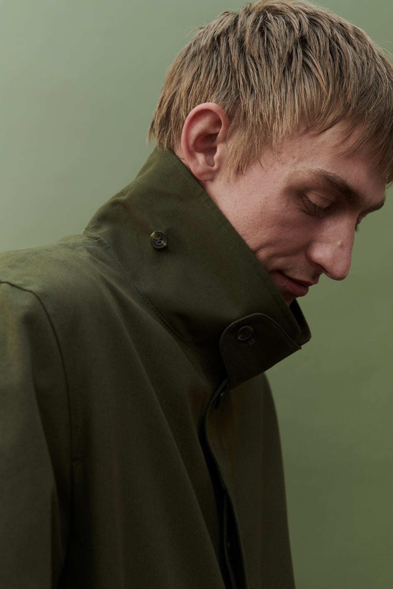 Image showing collar detail of men's raincoat in olive. Detachable collar strap