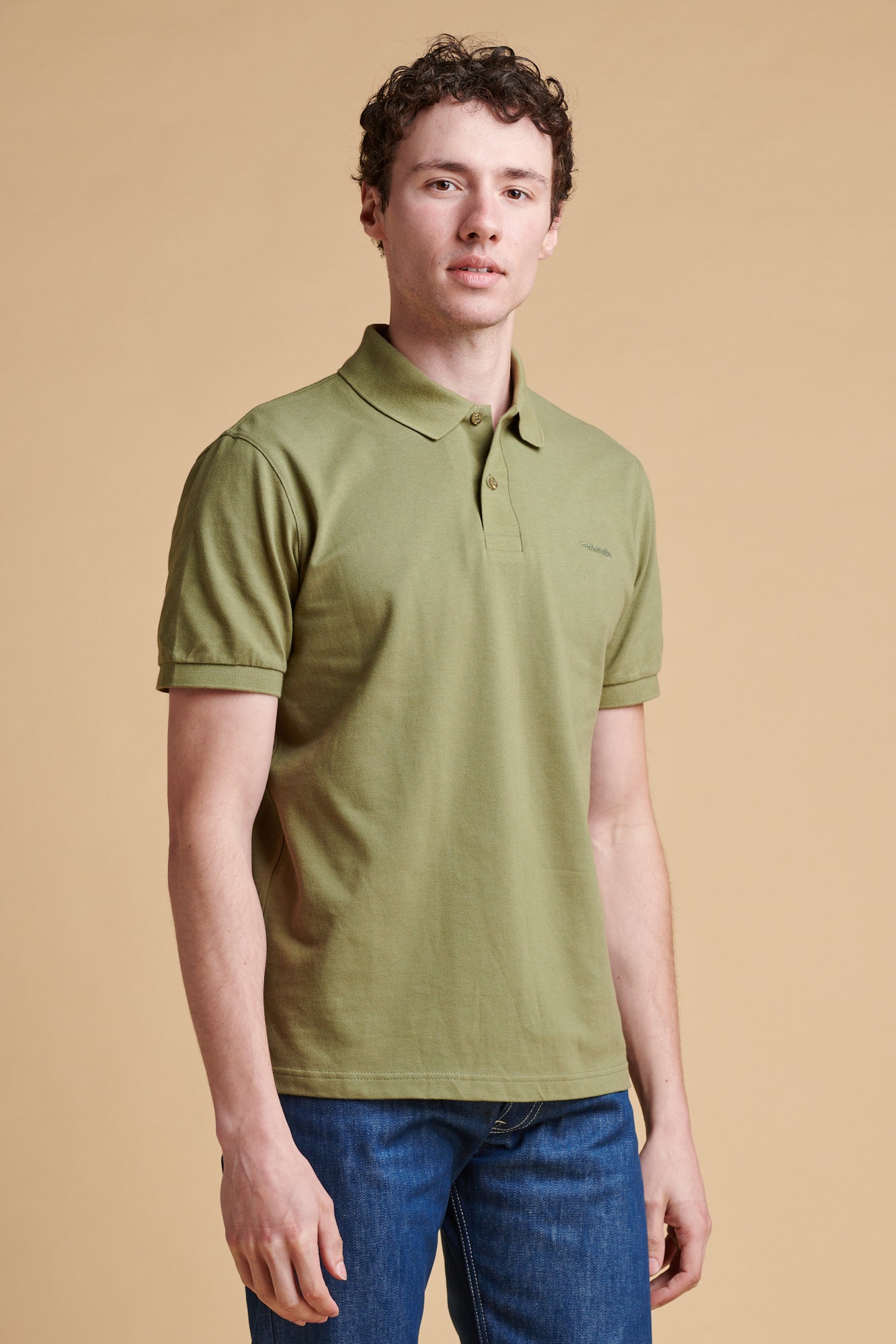Thigh up of male wearing short sleeve polo shirt in light olive.