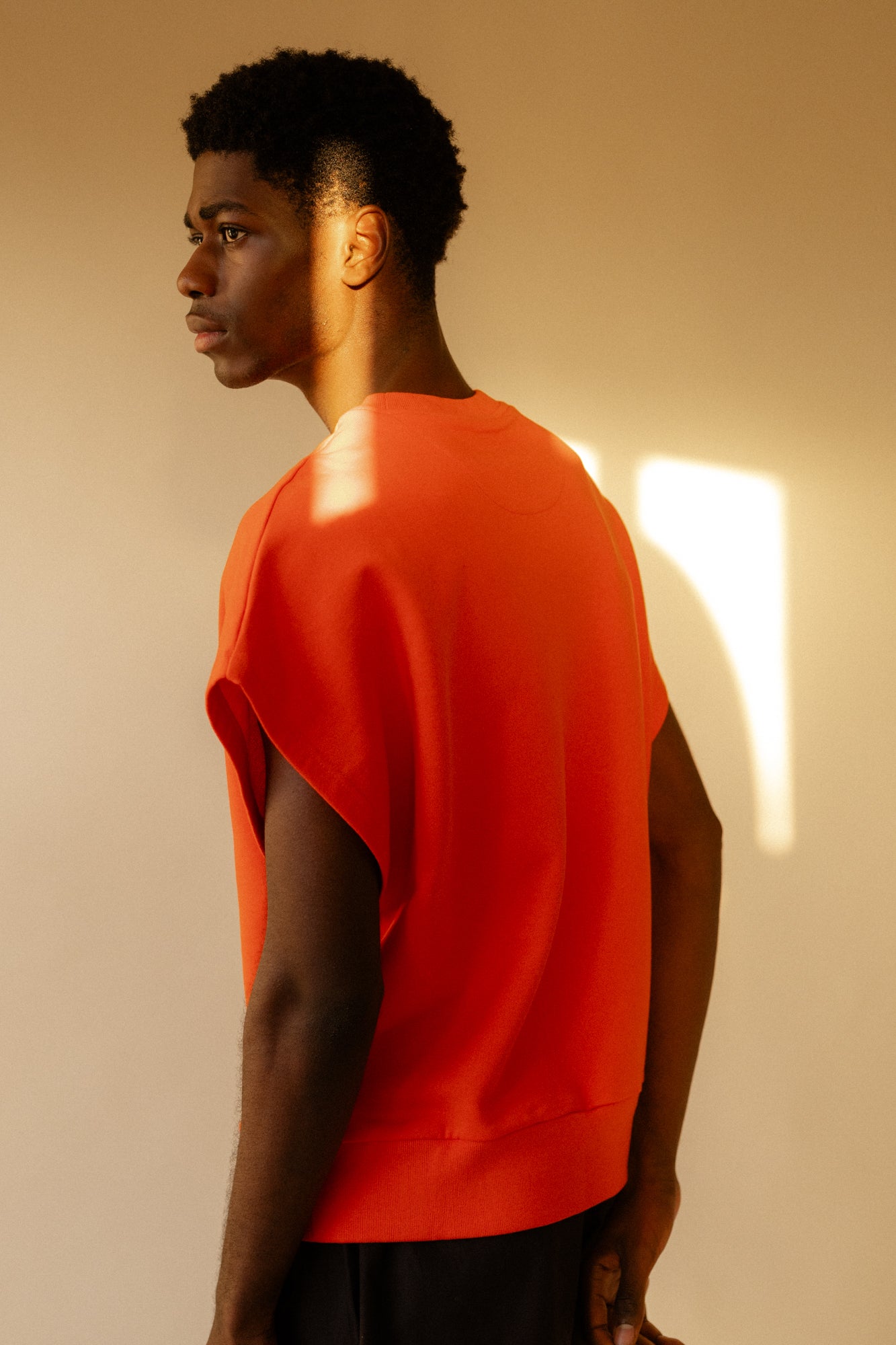 Image of the back of male wearing sleeveless sweatshirt plastic free in flame red 