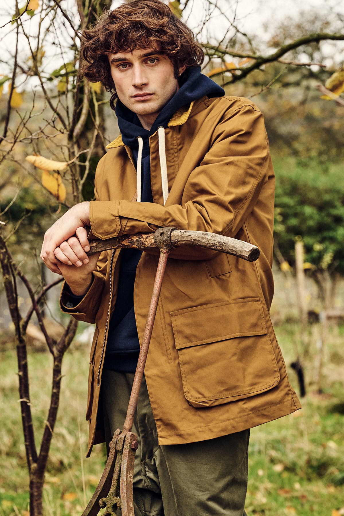 Man wearing a brown barn jacket holding a gardening tool.