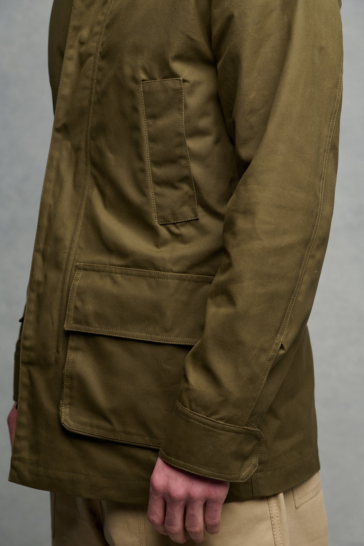 Close up of the side of males torso wearing barn jacket in olive, showing front pockets