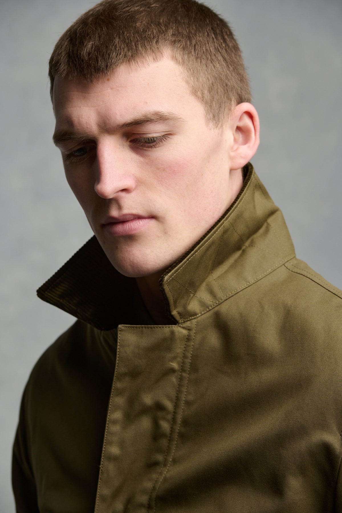 Close up portrait of brunet male wearing barn jacket in olive with cord collar up 