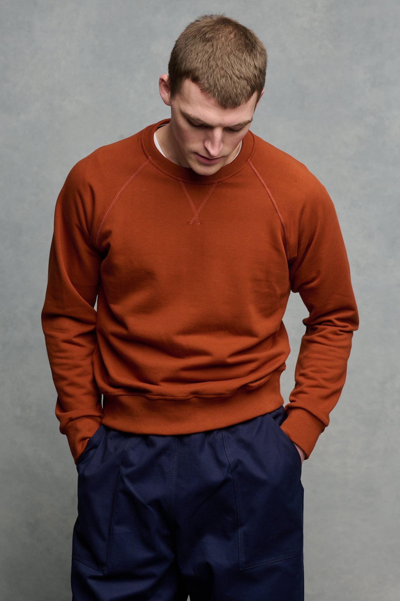 Thigh up image of male wearing cinnamon raglan sweatshirt
